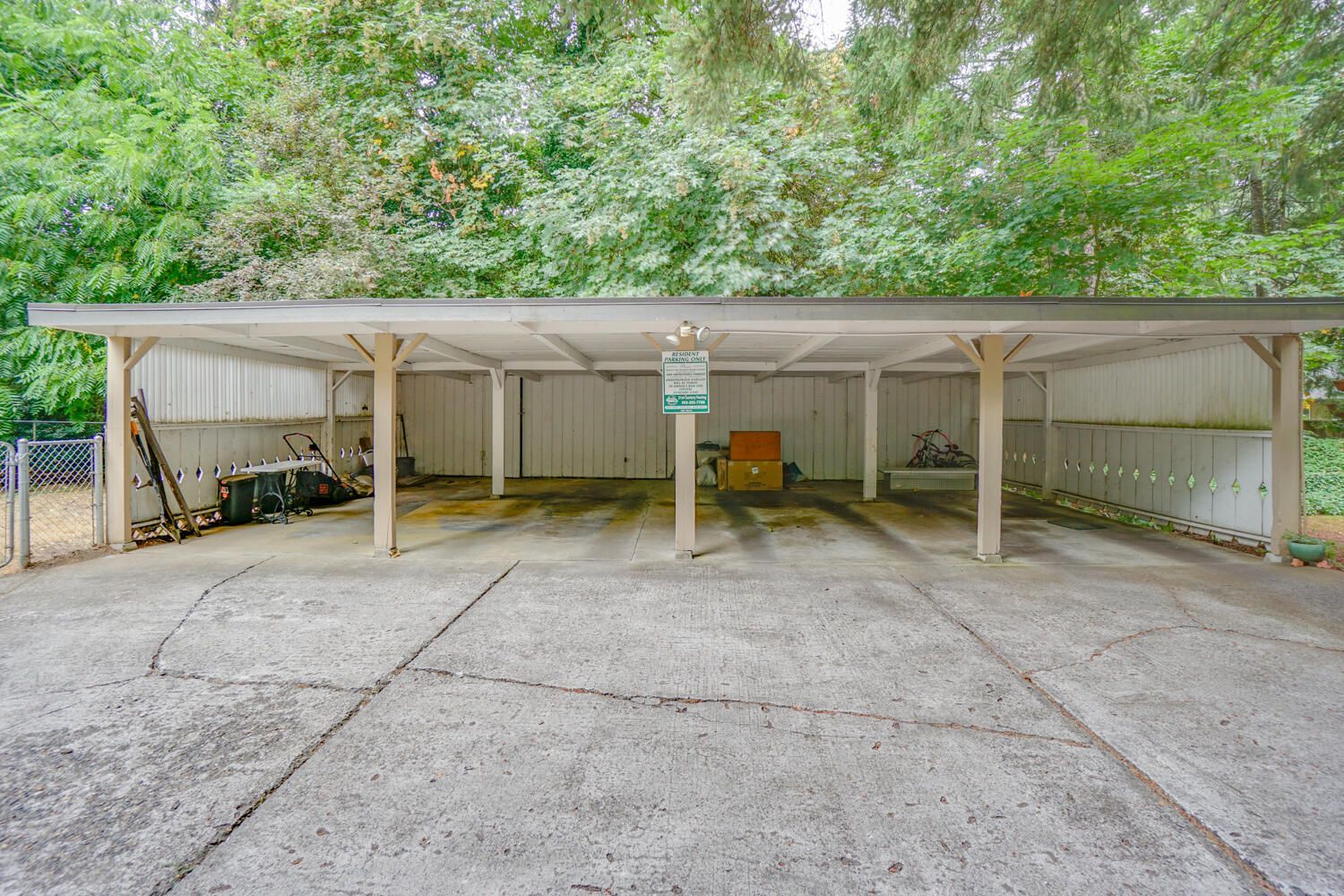 A parking lot with a covered area and trees in the background.