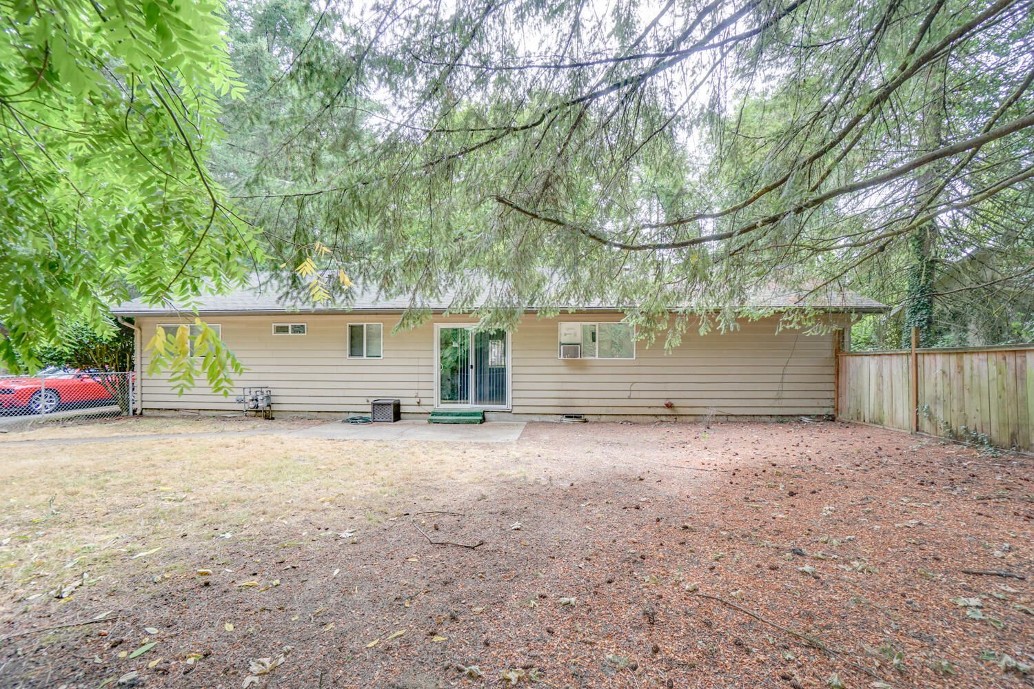 The backyard of a house with a fence and trees in the background.