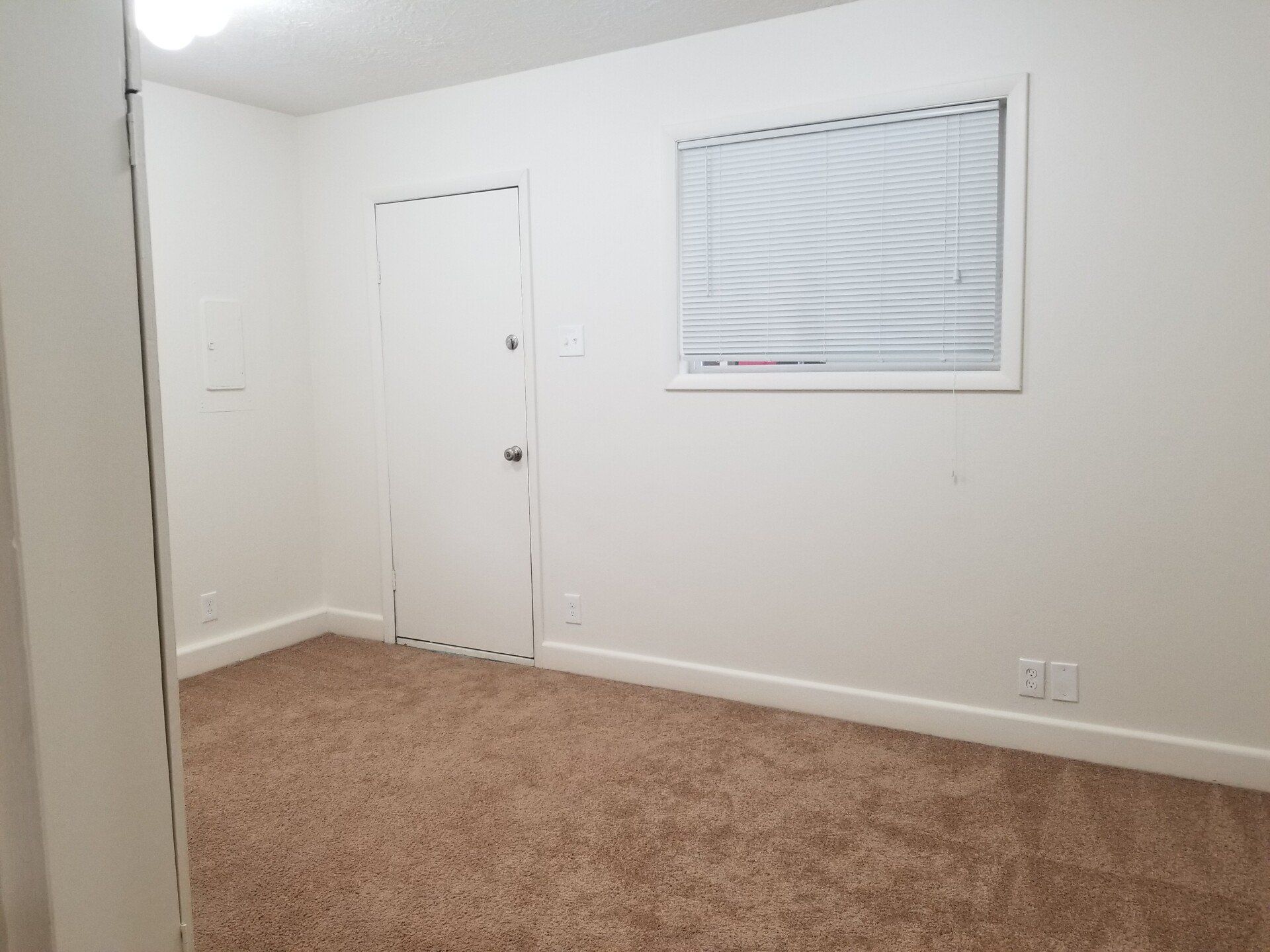 An empty bedroom with a window and blinds.