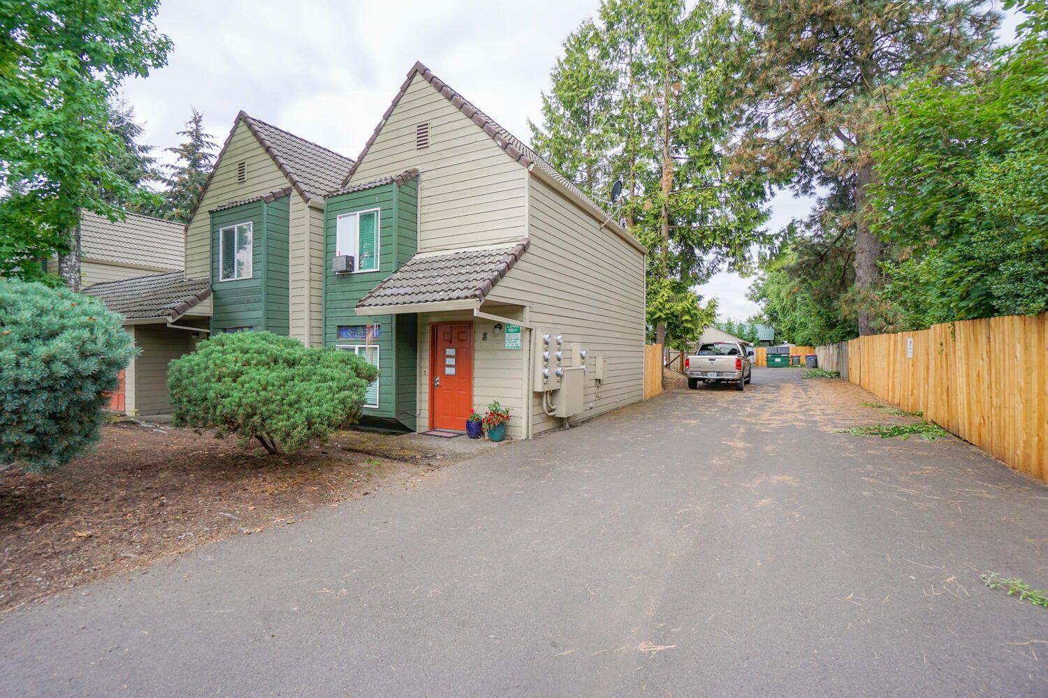 A green and white house with a wooden fence in front of it.