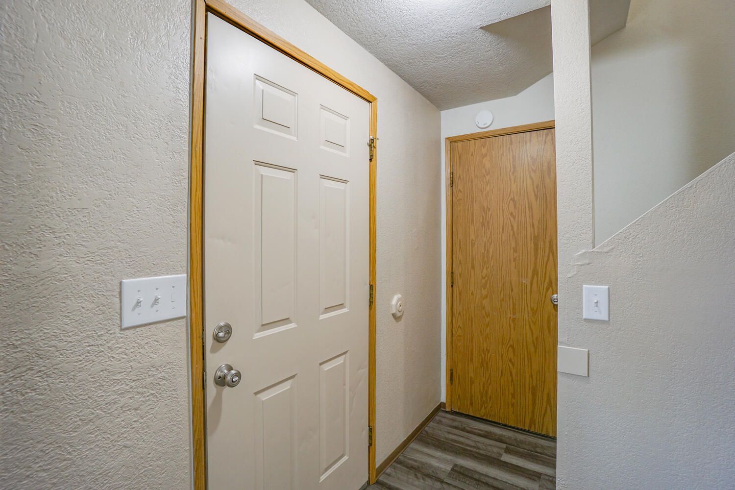 A hallway with a door and stairs in a house.