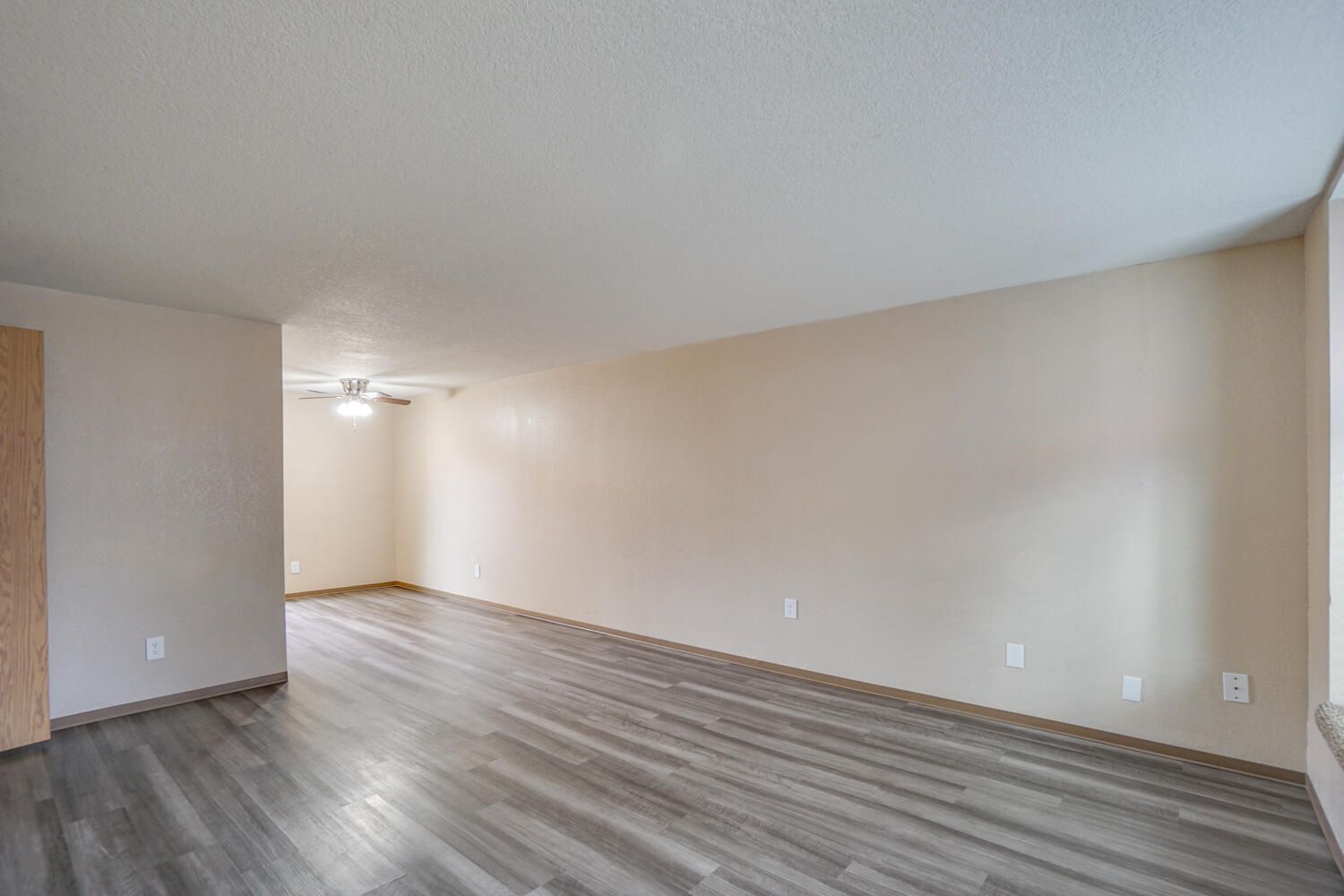 An empty living room with hardwood floors and a ceiling fan.