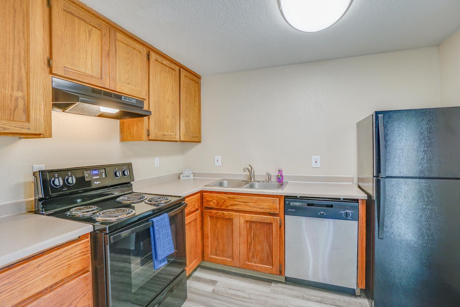 A kitchen with a stove , refrigerator , dishwasher and sink.