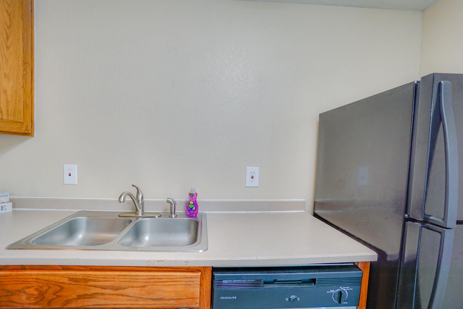 A kitchen with a sink , refrigerator and dishwasher.