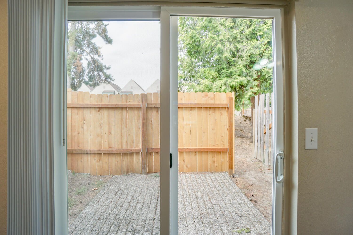 A sliding glass door leading to a backyard with a wooden fence.