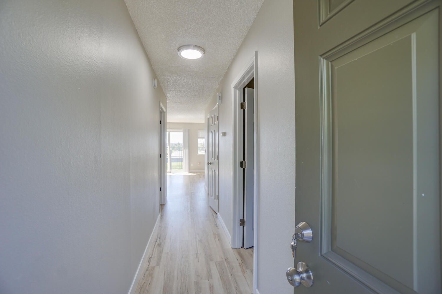 A long hallway with a door open leading to a living room.