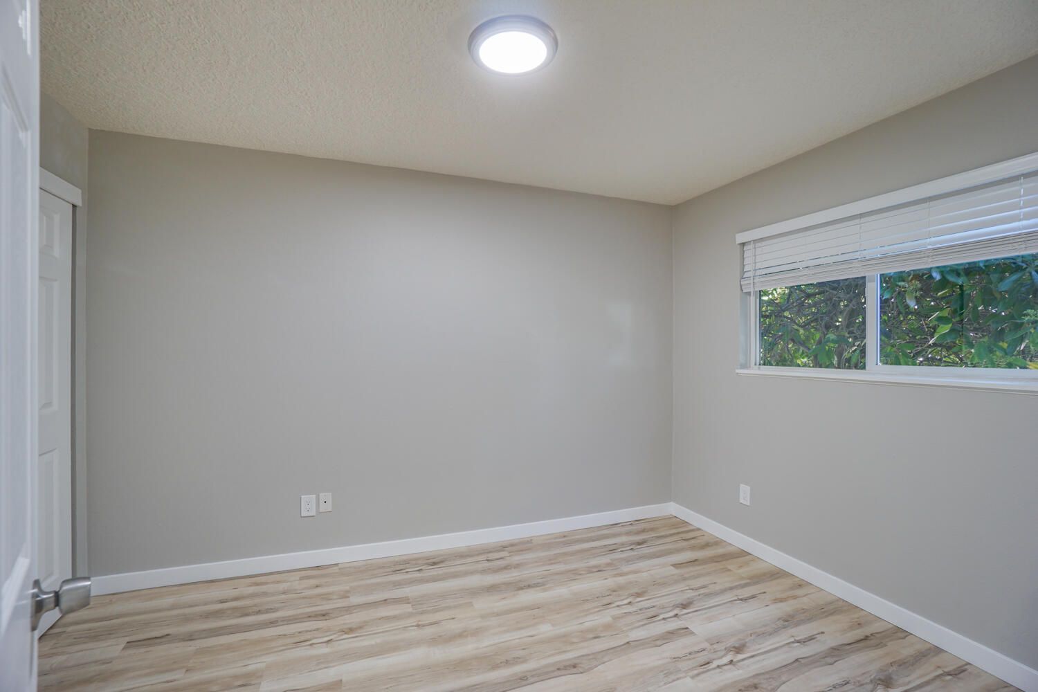 An empty bedroom with hardwood floors and a window.