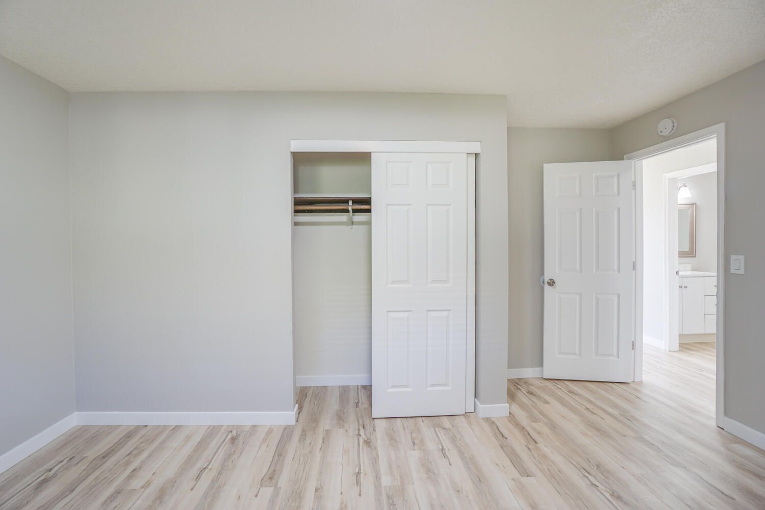 An empty bedroom with a closet and hardwood floors.
