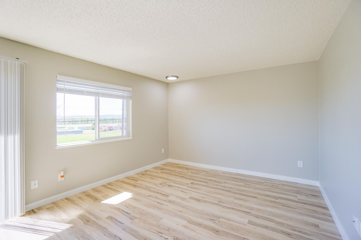 An empty living room with hardwood floors and a window.