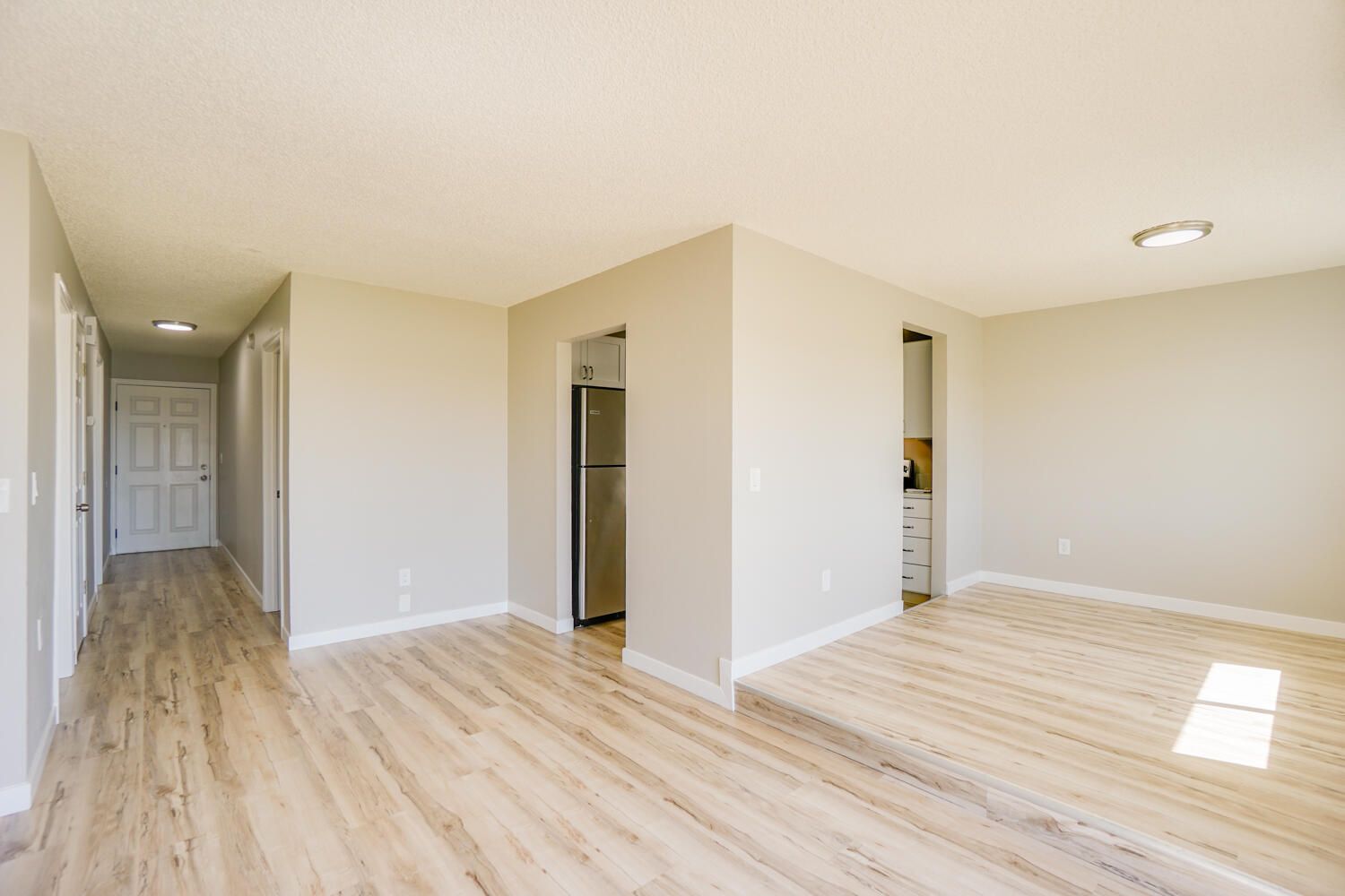 An empty living room with hardwood floors and white walls