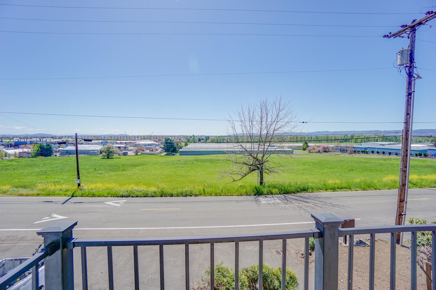A view of a field from a balcony overlooking a road.