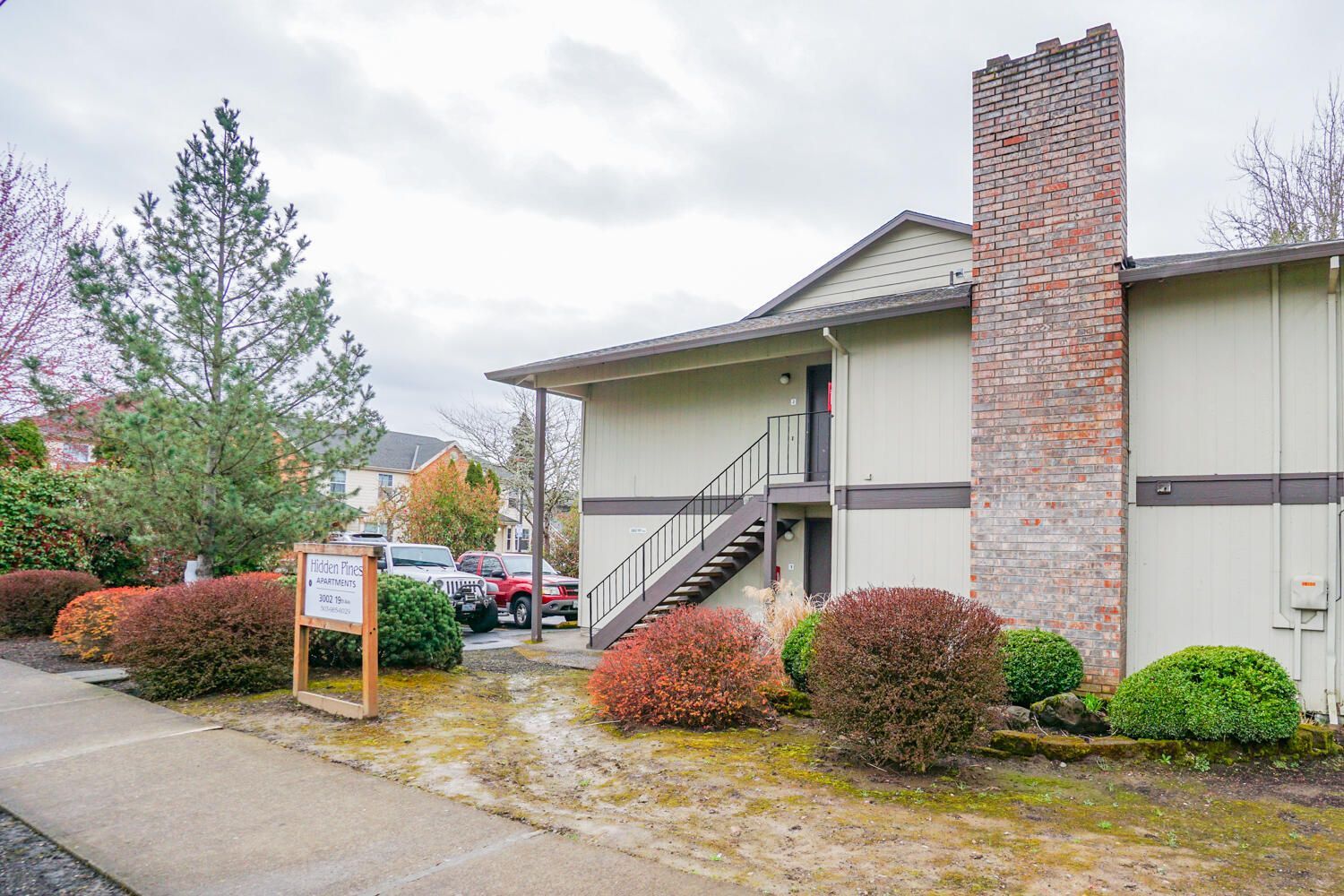 A white apartment building with a brick chimney and stairs.