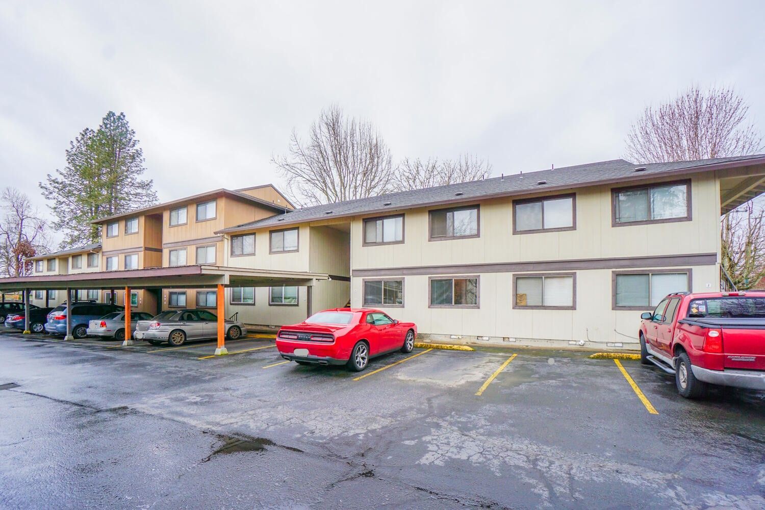 A large apartment building with a lot of cars parked in front of it.