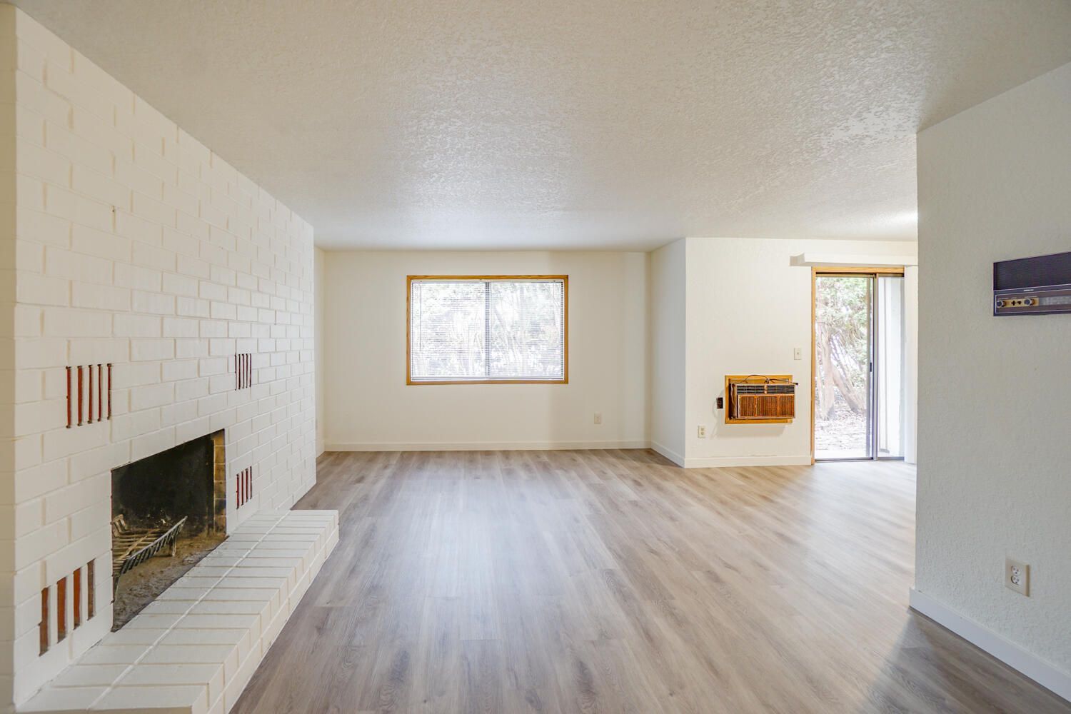 An empty living room with a fireplace and hardwood floors.
