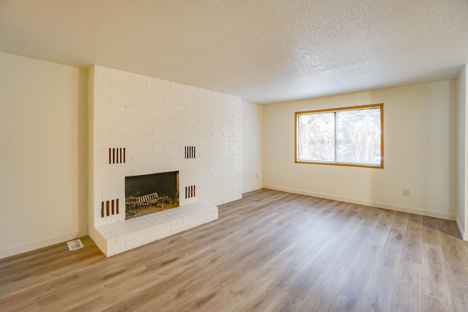 An empty living room with a fireplace and a window.