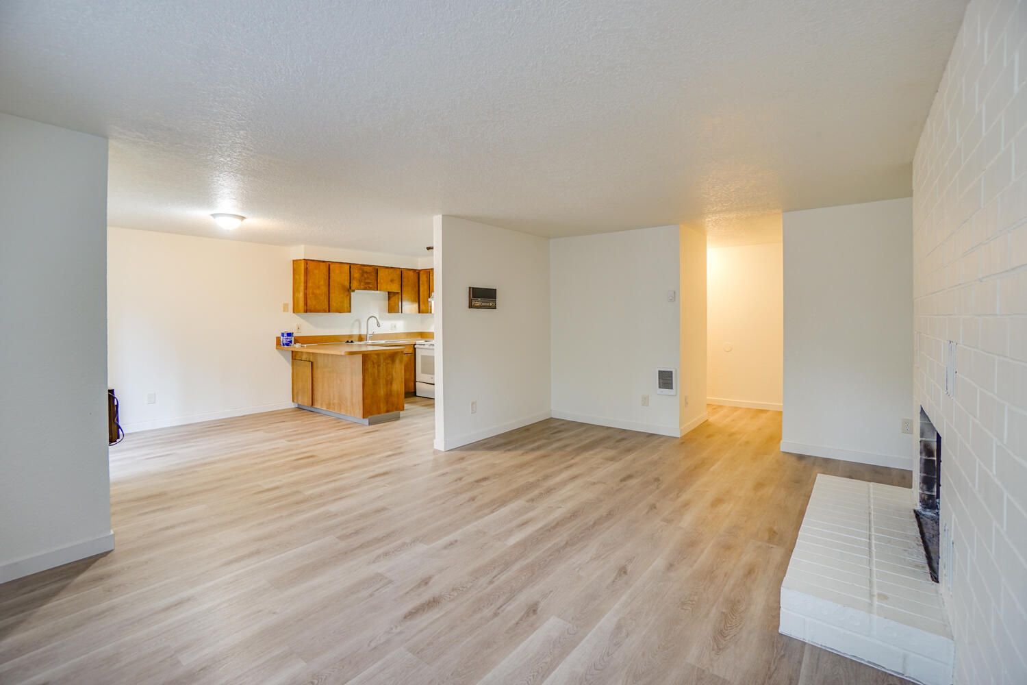An empty living room with hardwood floors and a fireplace.