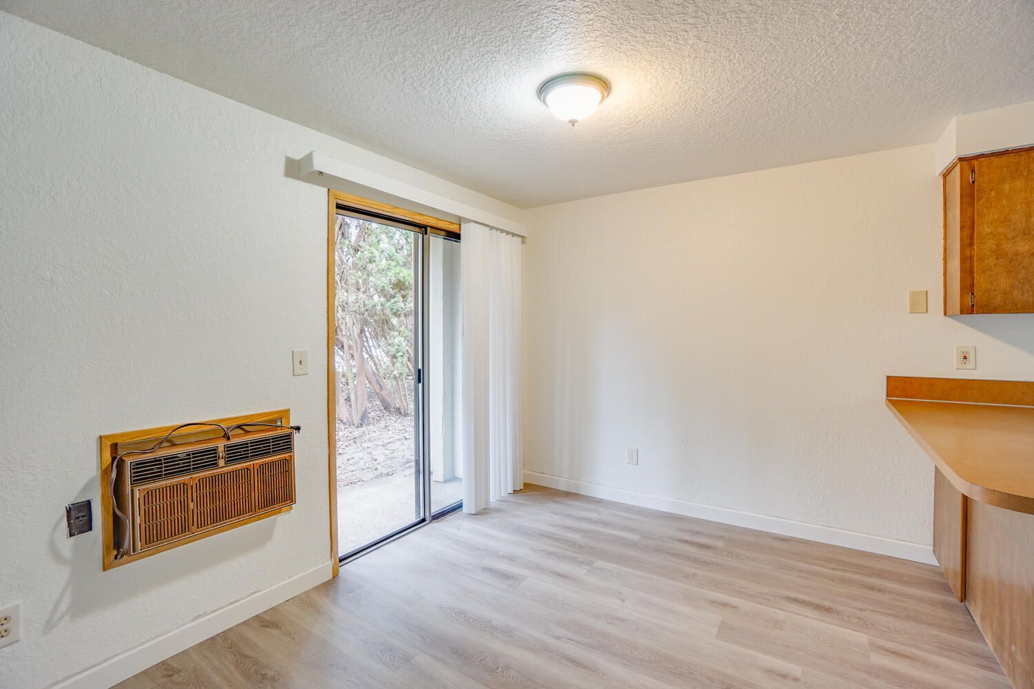 An empty room with a sliding glass door and wooden floors.