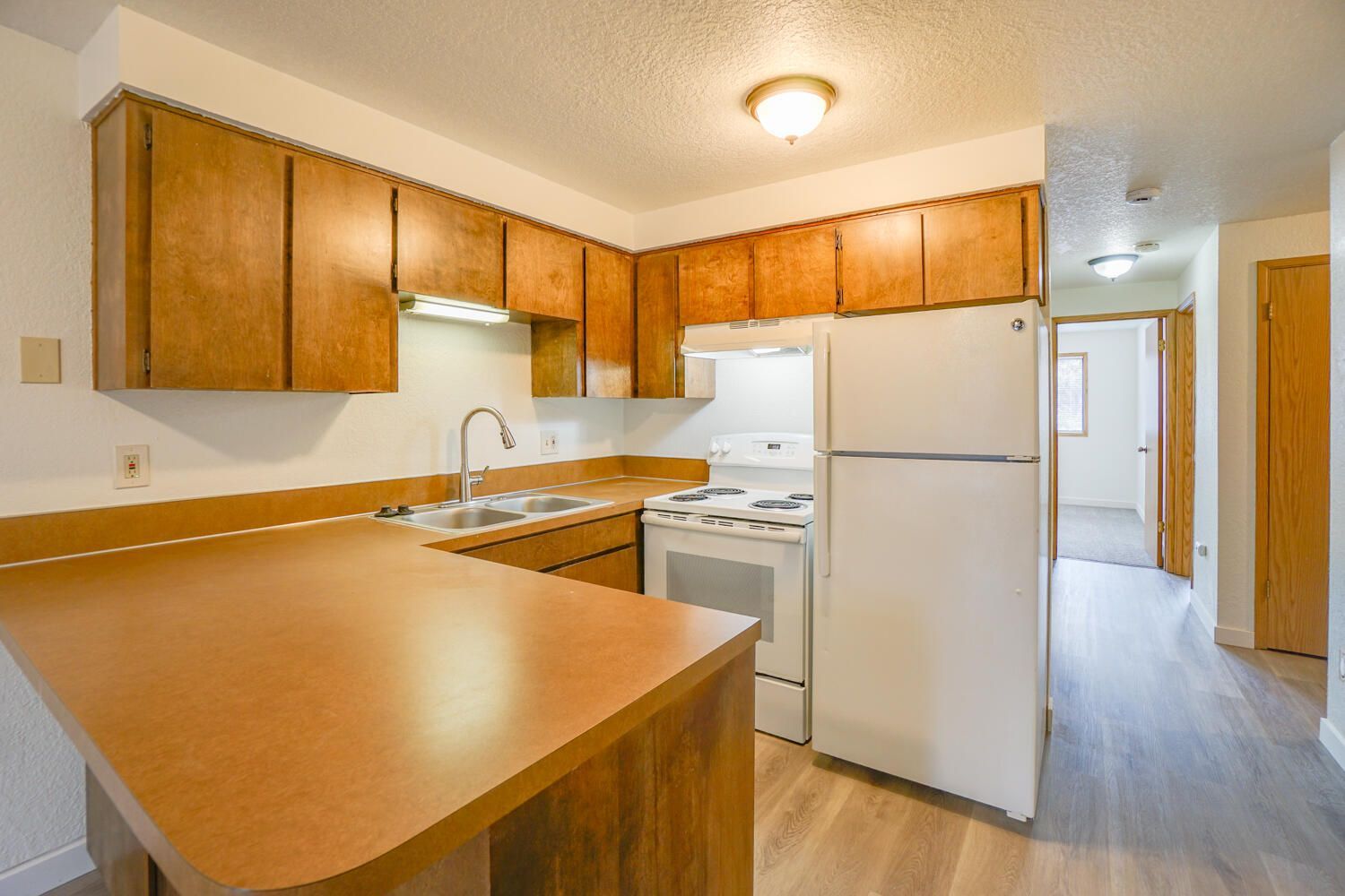 A kitchen with wooden cabinets and a white refrigerator.
