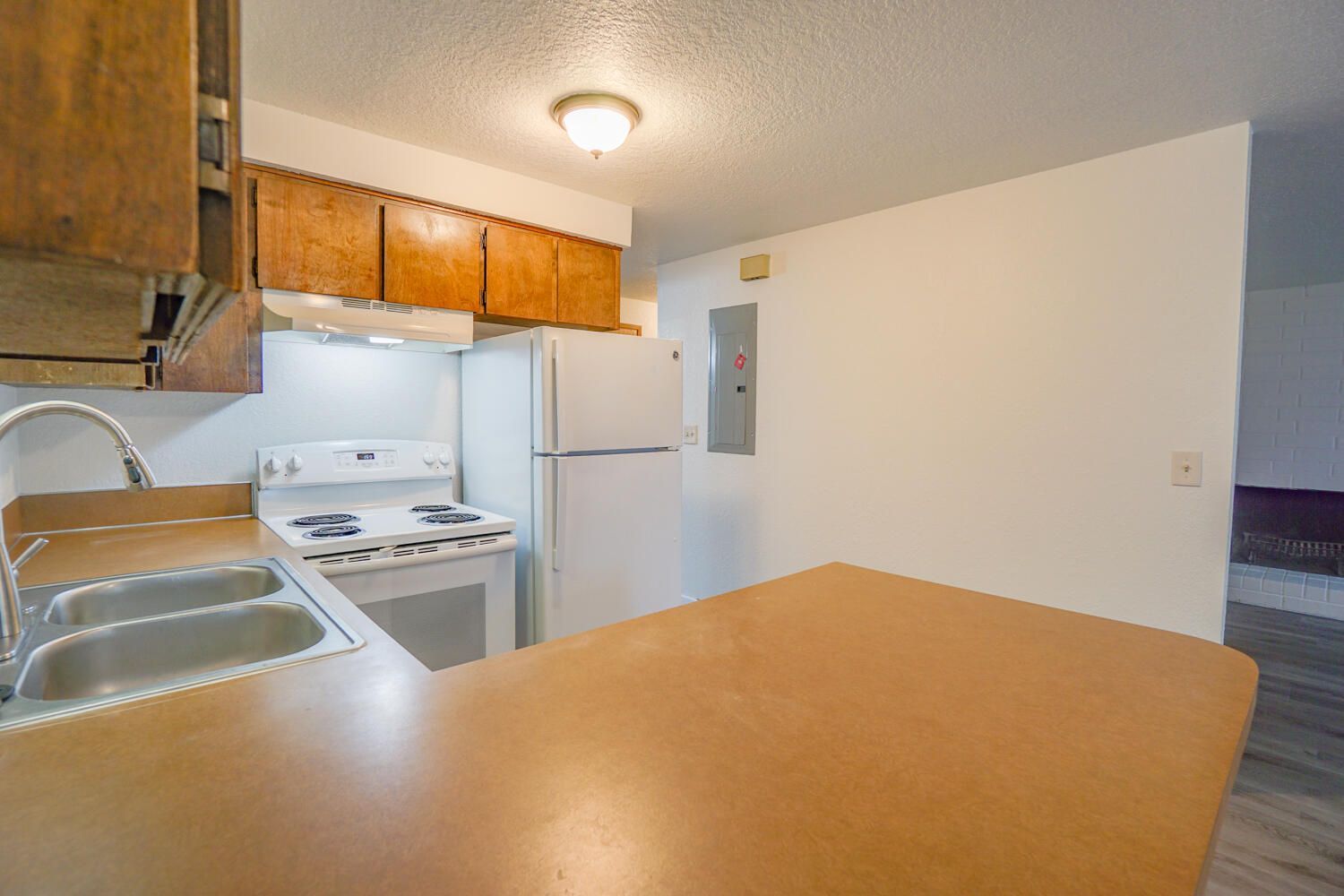 A kitchen with a stove , refrigerator , sink and wooden cabinets.
