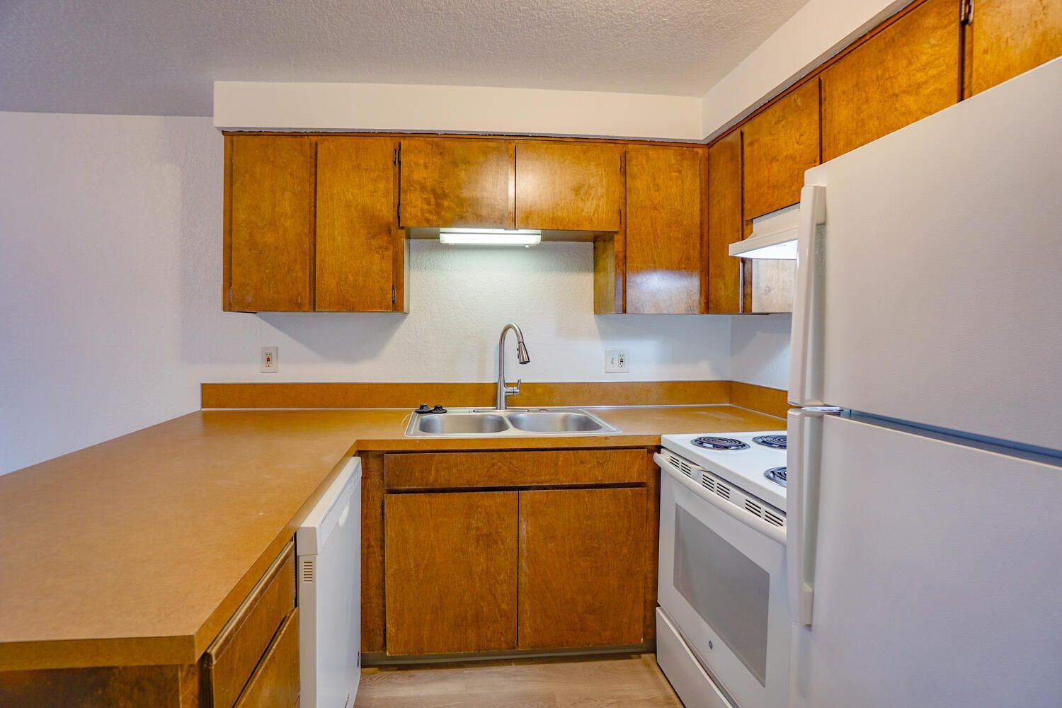 A kitchen with wooden cabinets and a white refrigerator