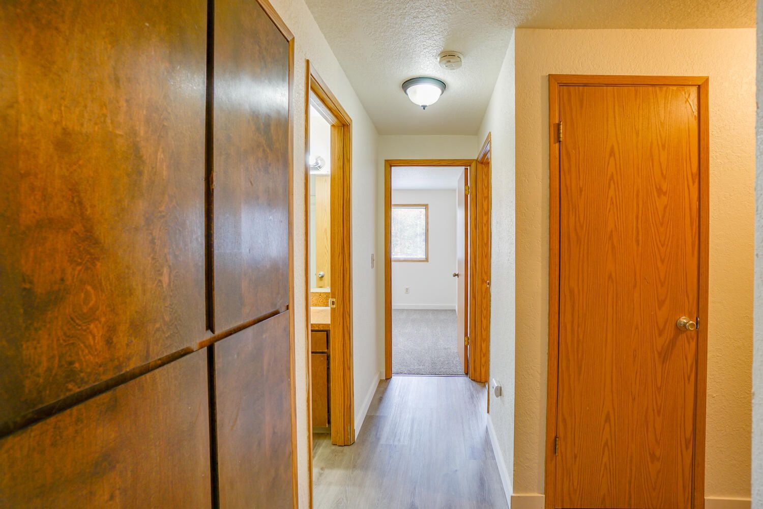 A hallway in a house with wooden doors leading to different rooms.