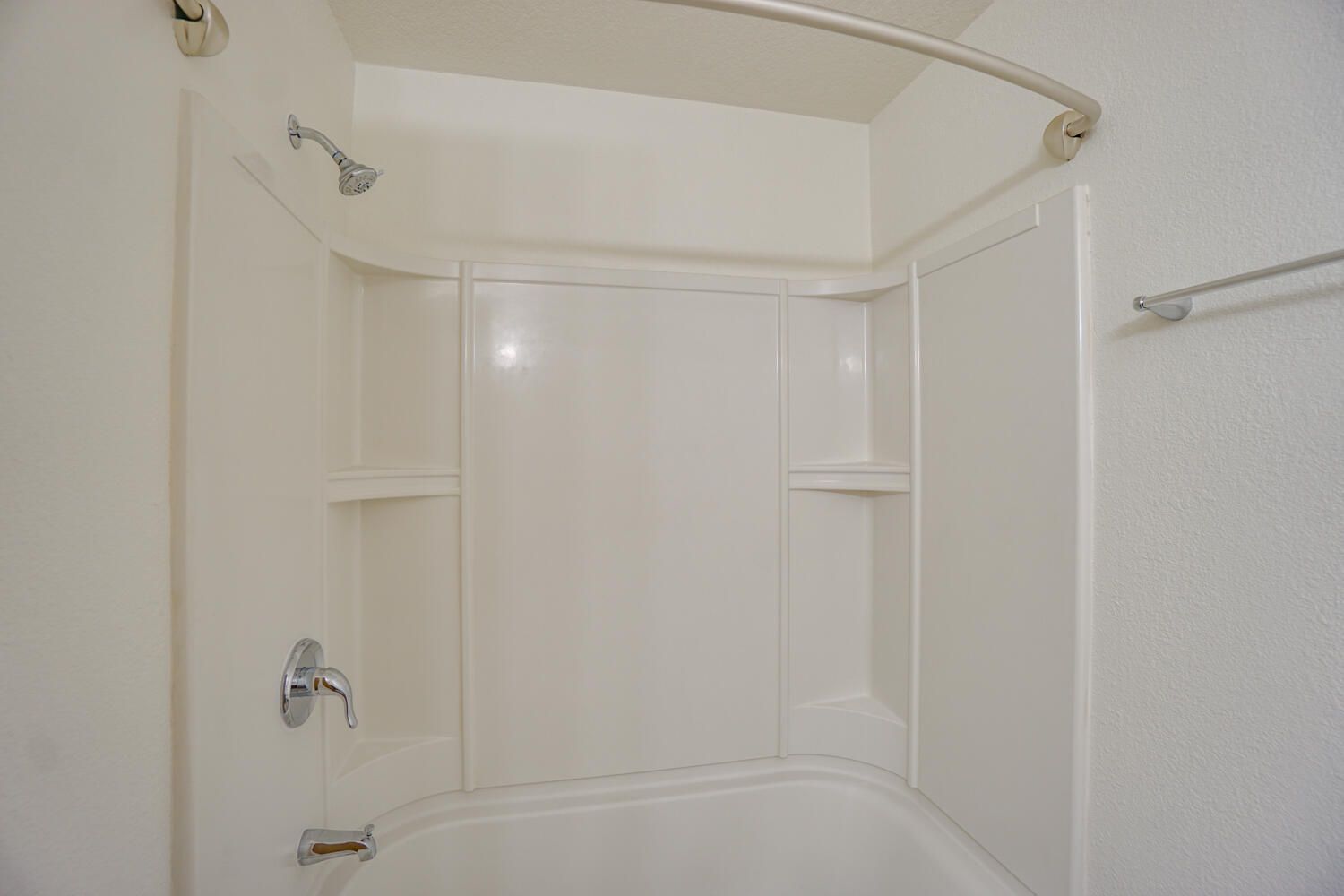A bathroom with a bathtub , shower , and shelves.