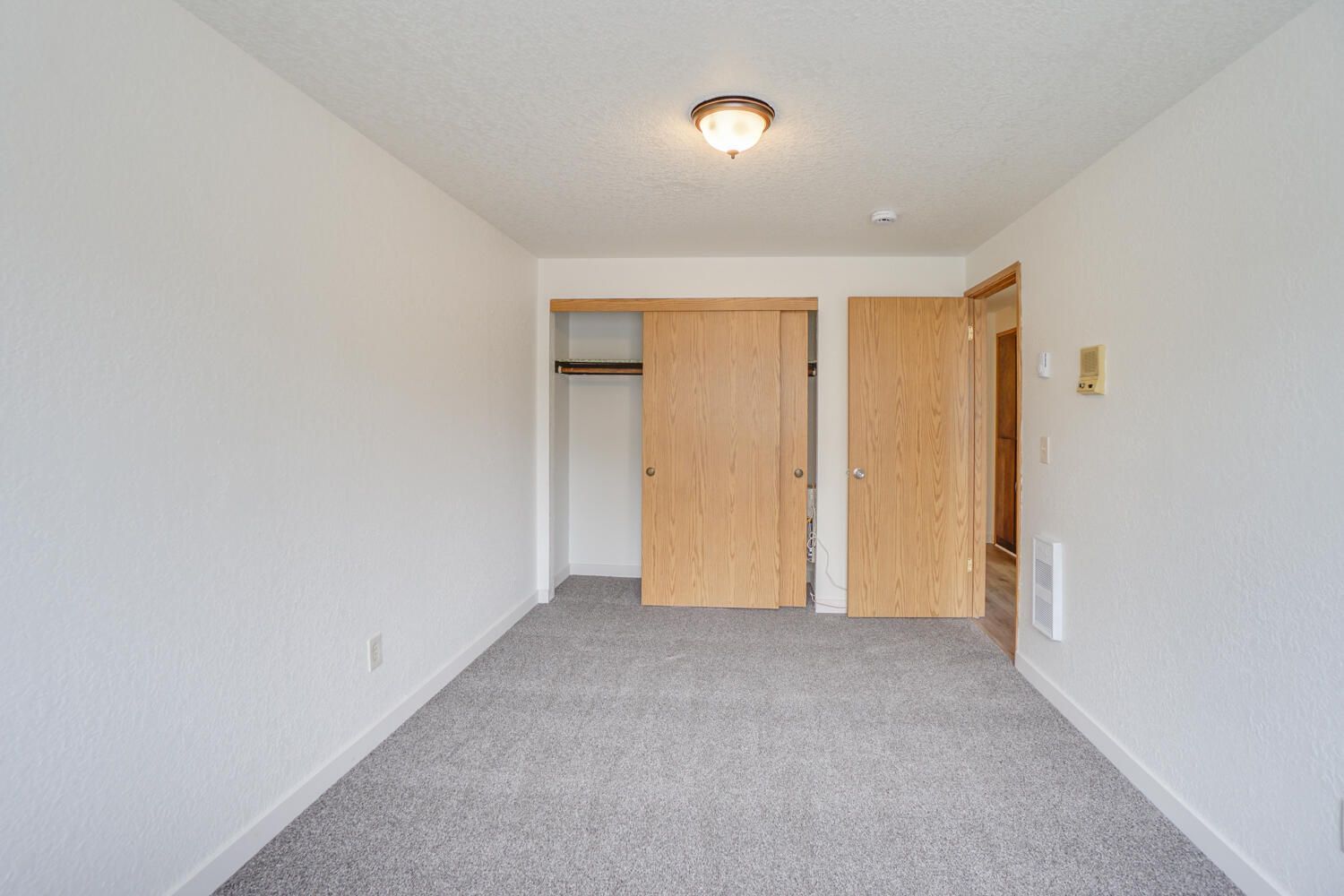 An empty bedroom with a closet and sliding doors