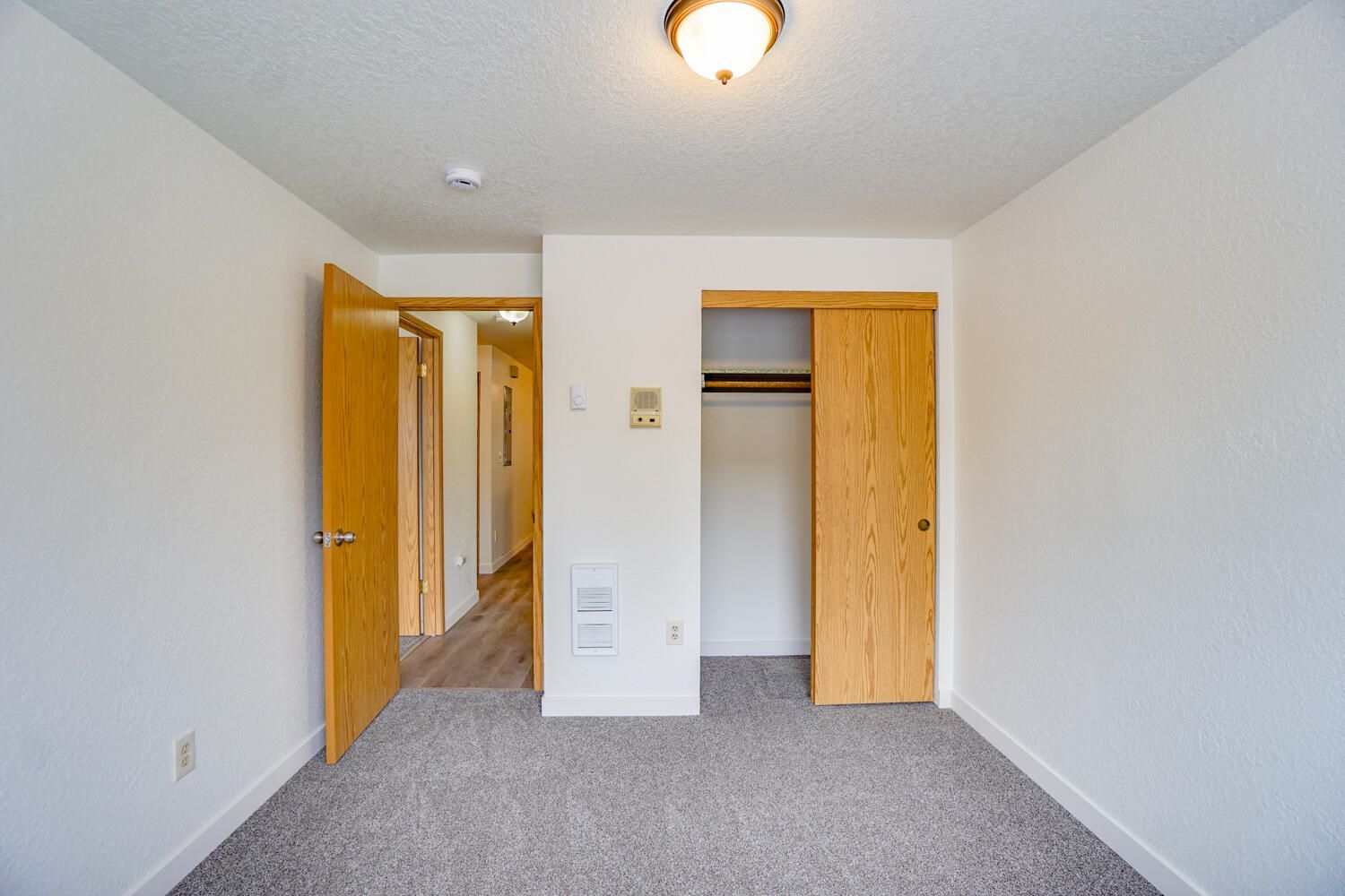 An empty bedroom with a closet and a light on the ceiling.