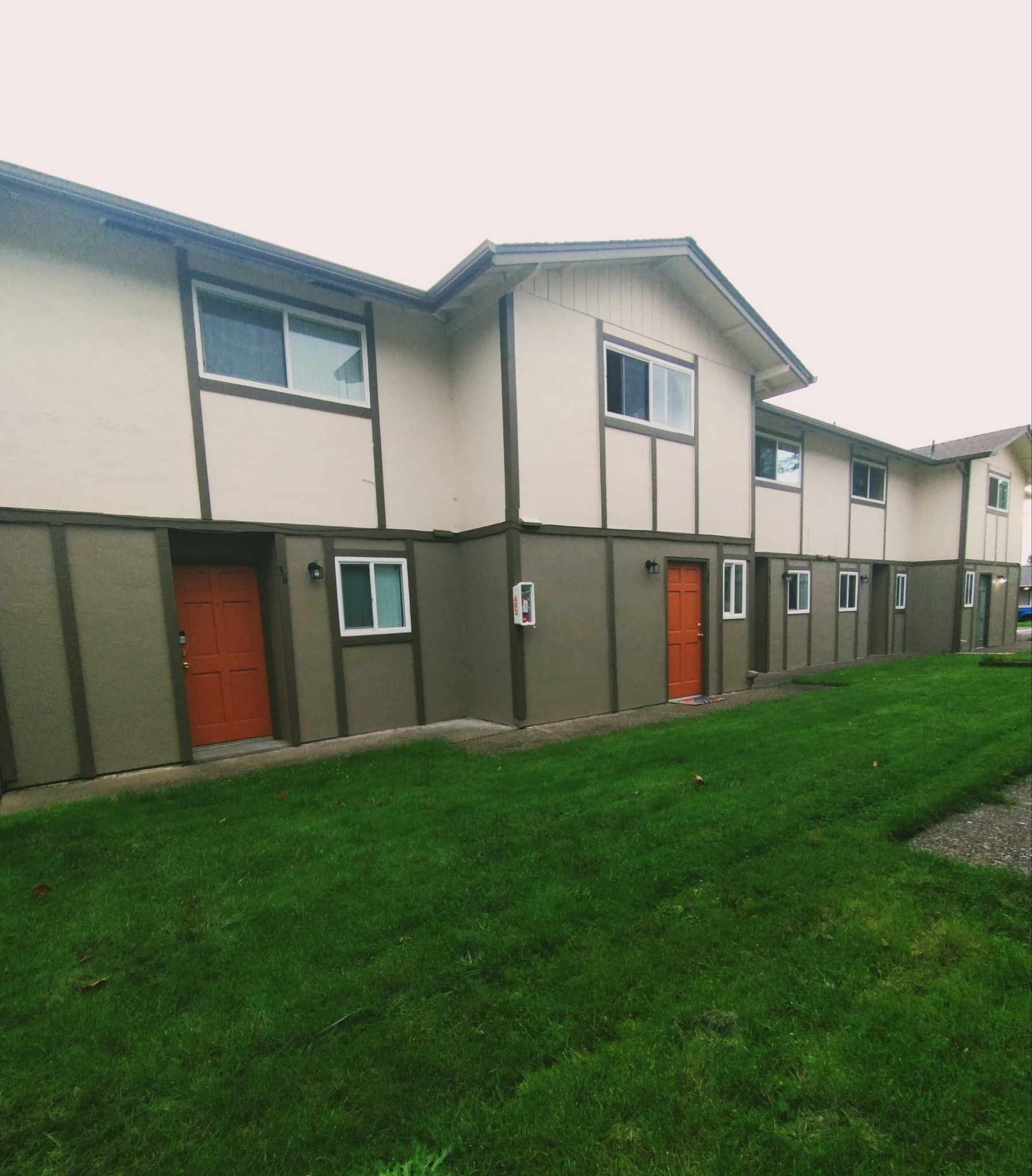 A row of apartment buildings with a lush green lawn in front of them
