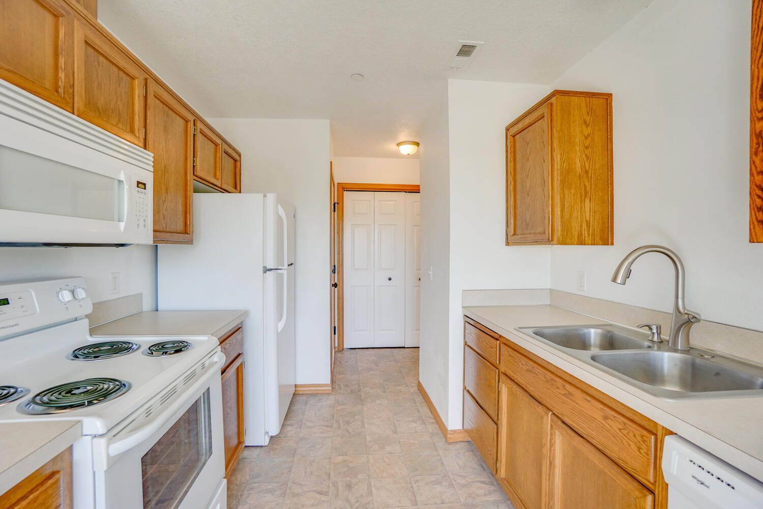 A kitchen with a stove , sink , refrigerator and microwave.