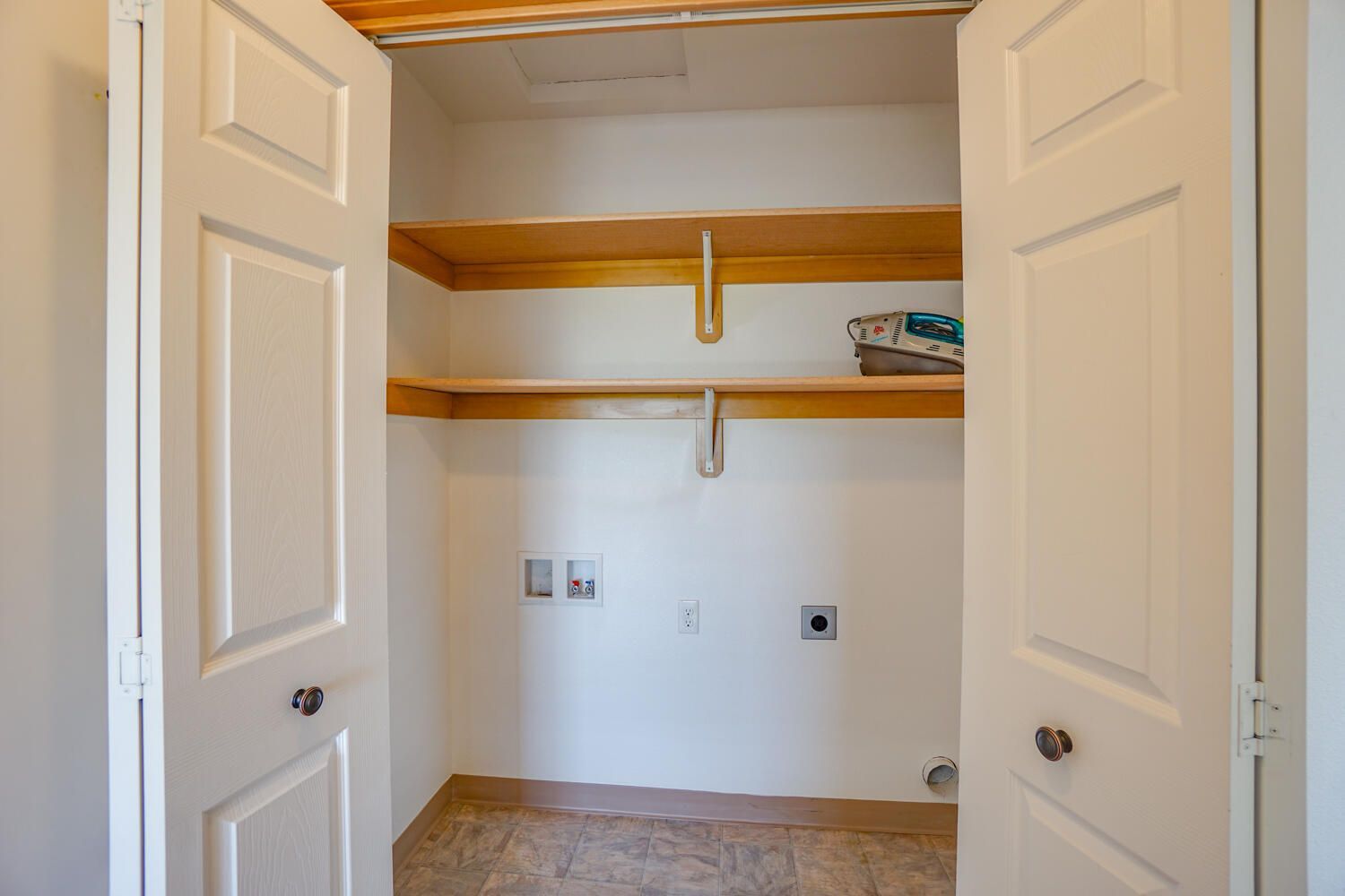 A laundry room with a washer and dryer and shelves.