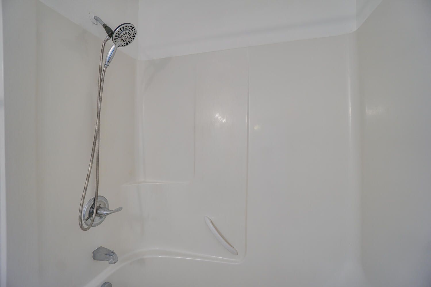A shower with a shower head and a bathtub in a bathroom.