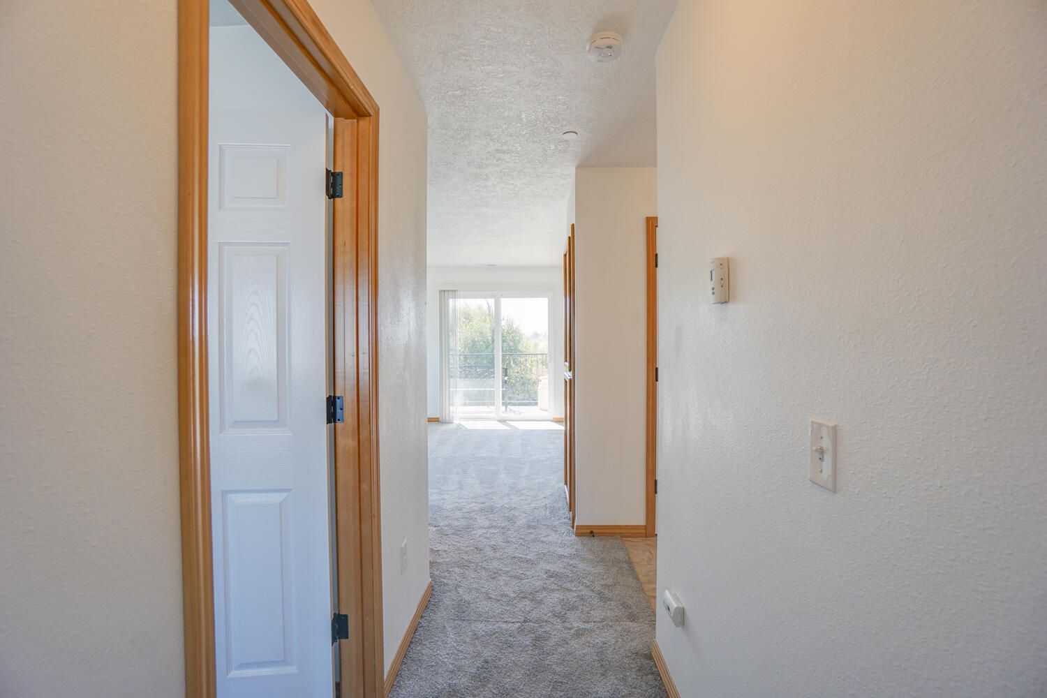 A hallway in a house with a sliding glass door leading to a living room.