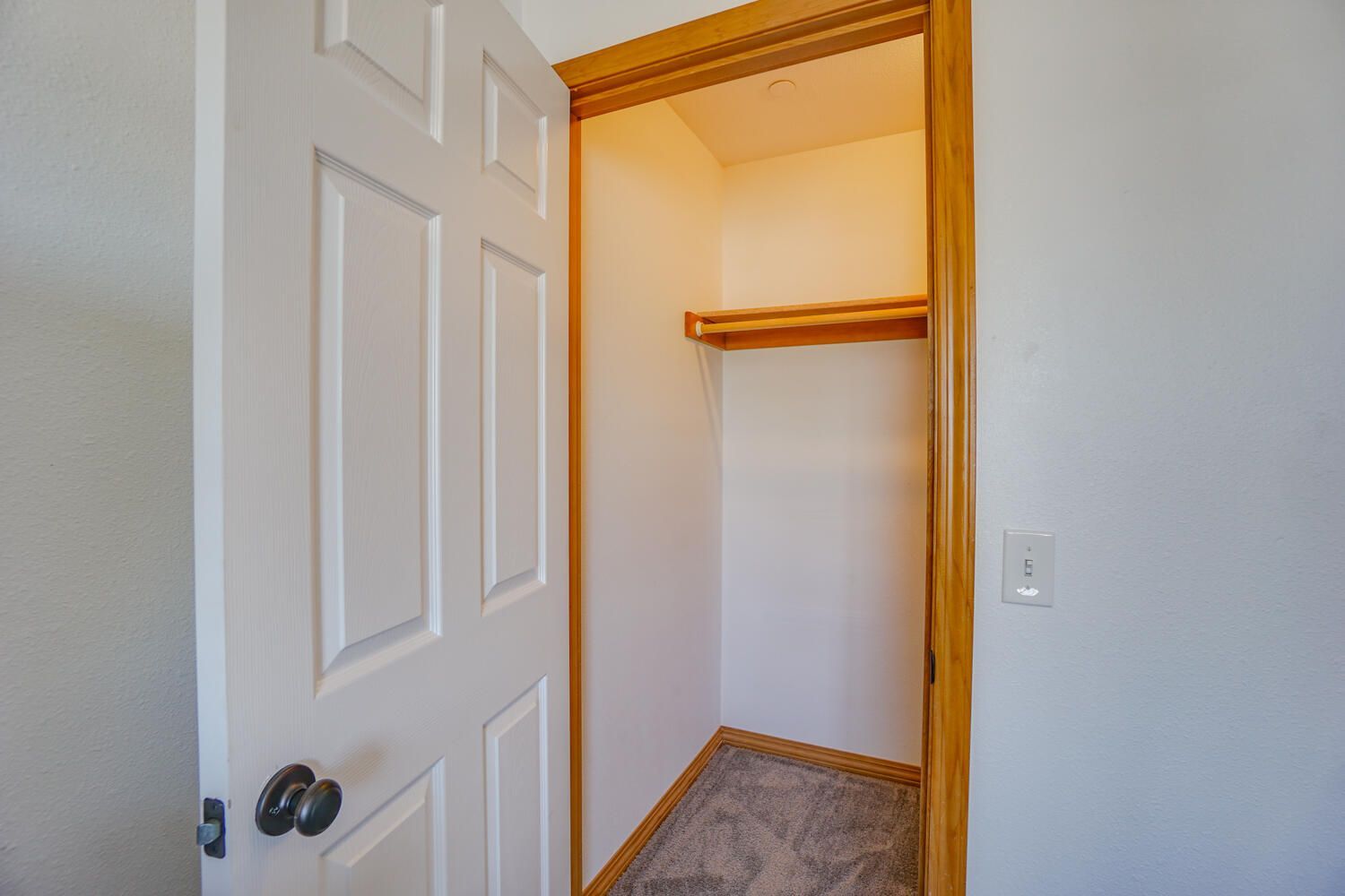 An empty closet in a bedroom with a door open.
