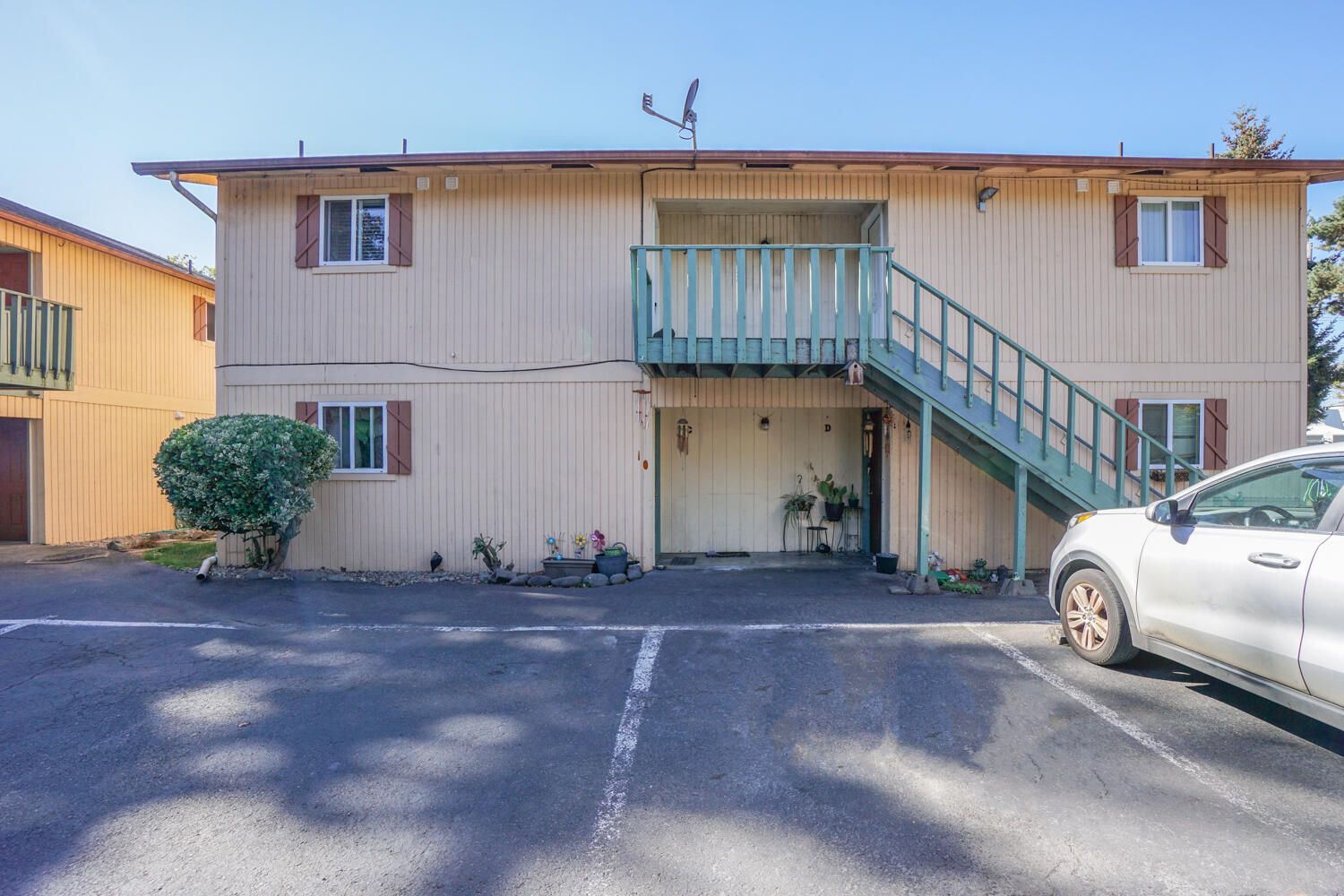 A white car is parked in front of a building with stairs.