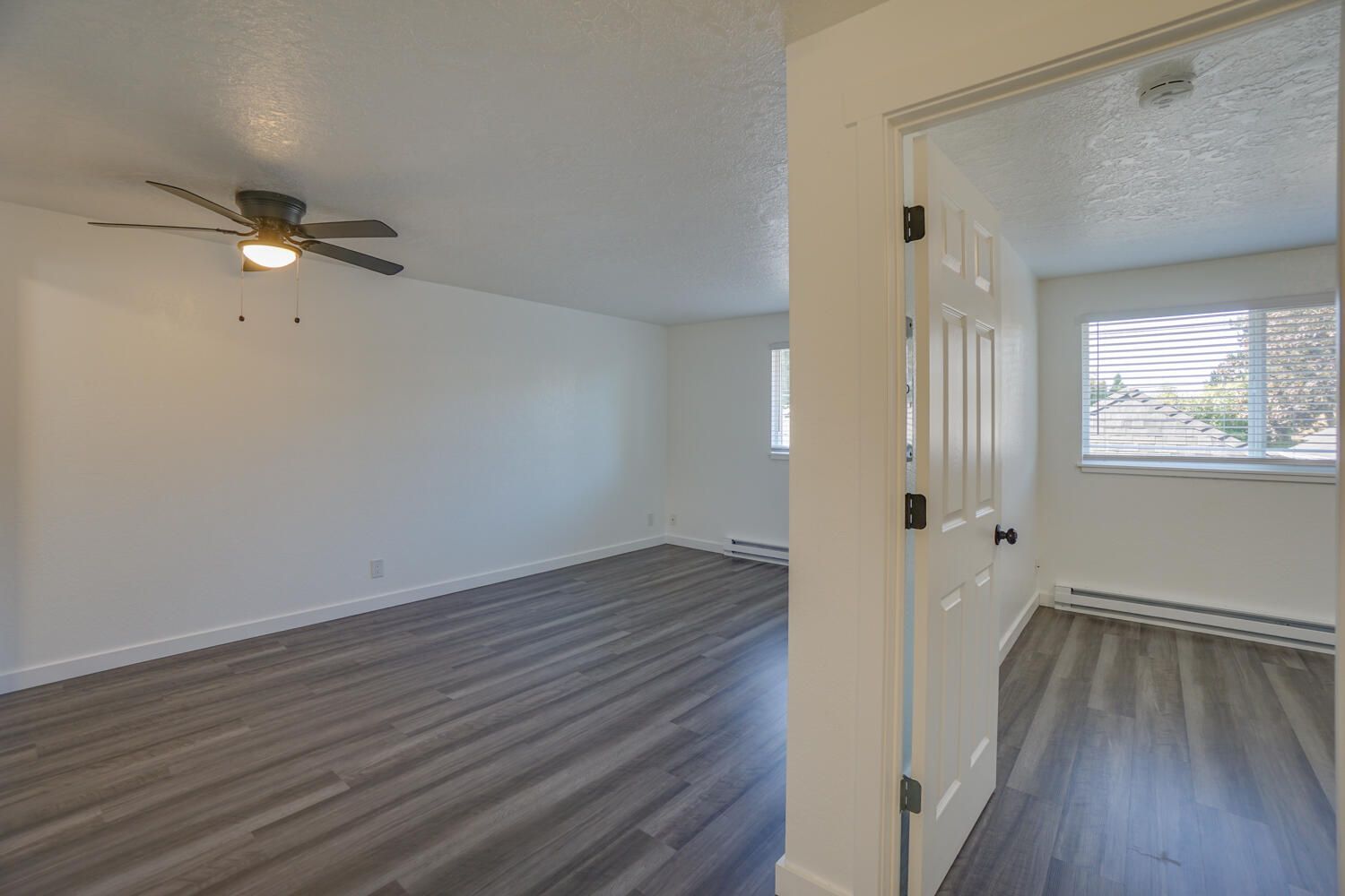 An empty room with a ceiling fan and a window.