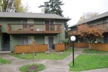 A green apartment building with a balcony and stairs.