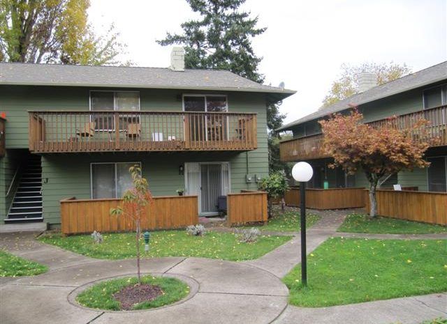 A green apartment building with a balcony and stairs