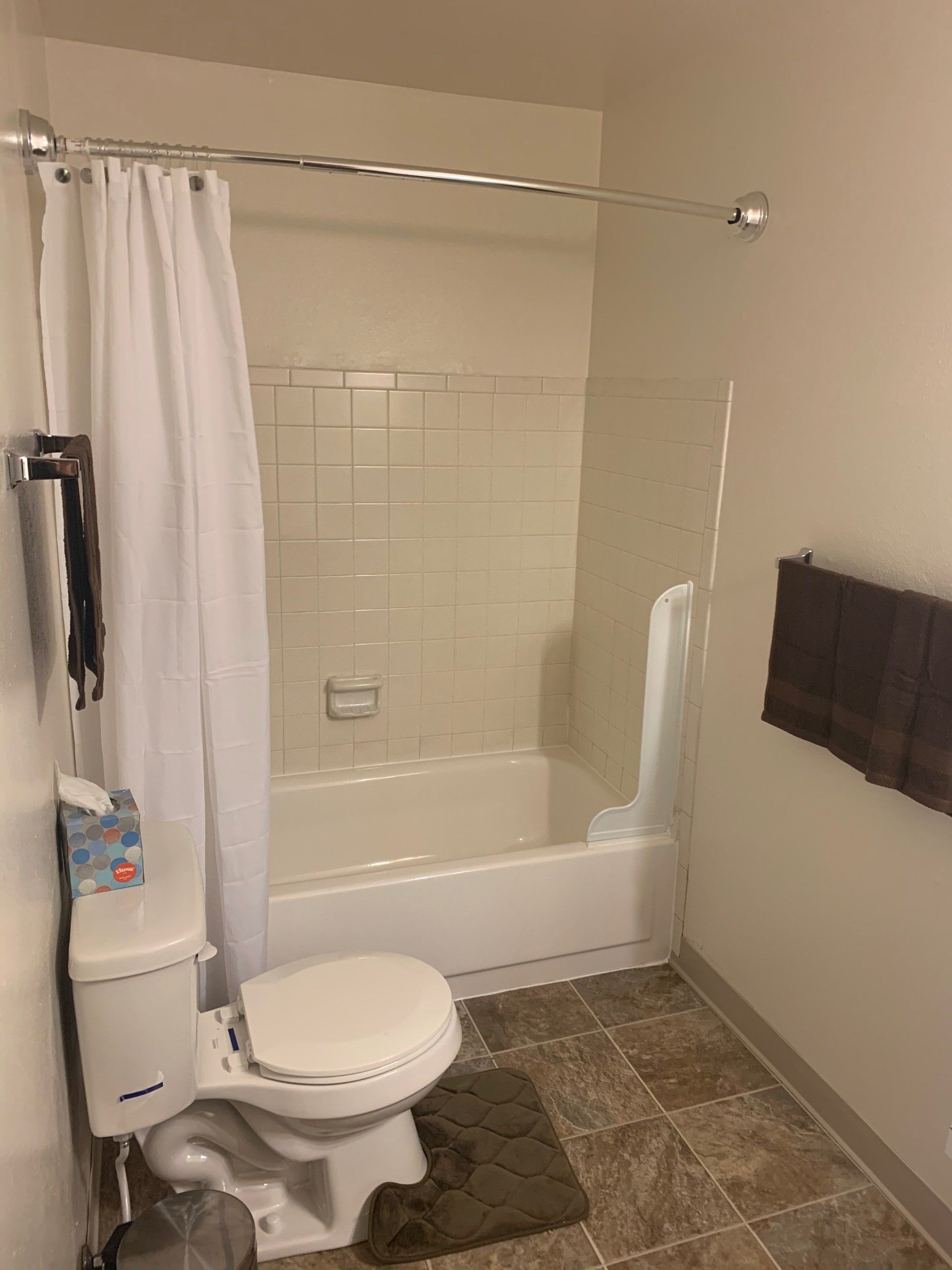 A bathroom with a toilet , bathtub and shower curtain.