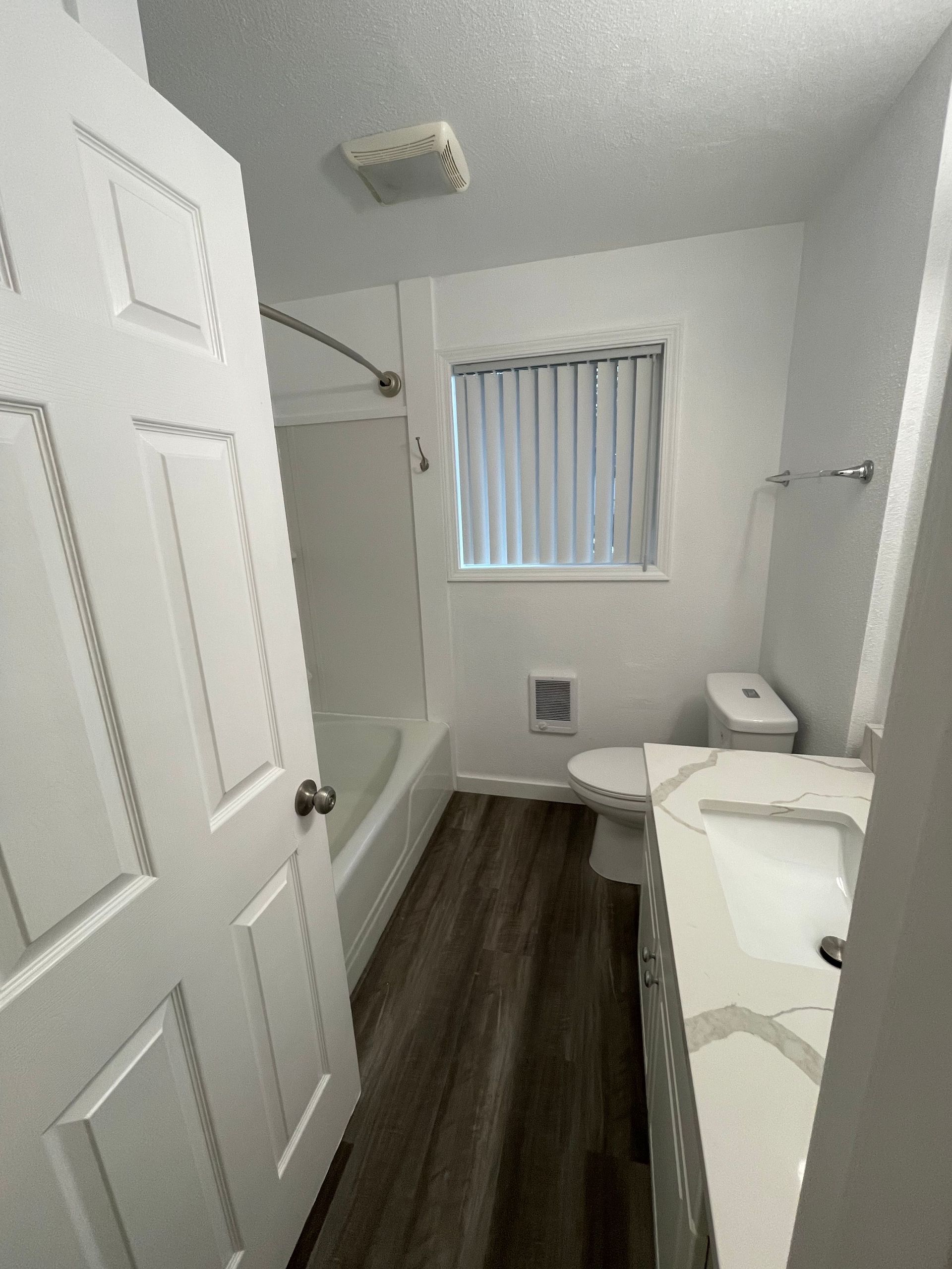 A bathroom with a toilet , sink , tub and window