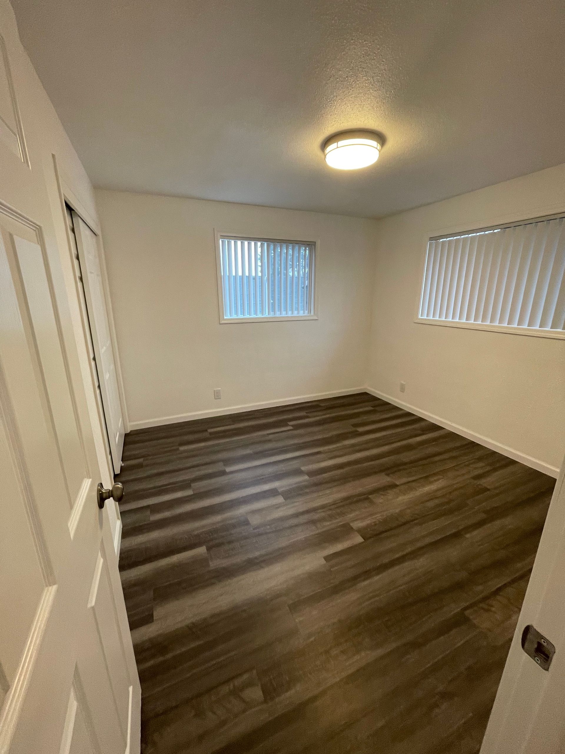 A bedroom with hardwood floors and a window.