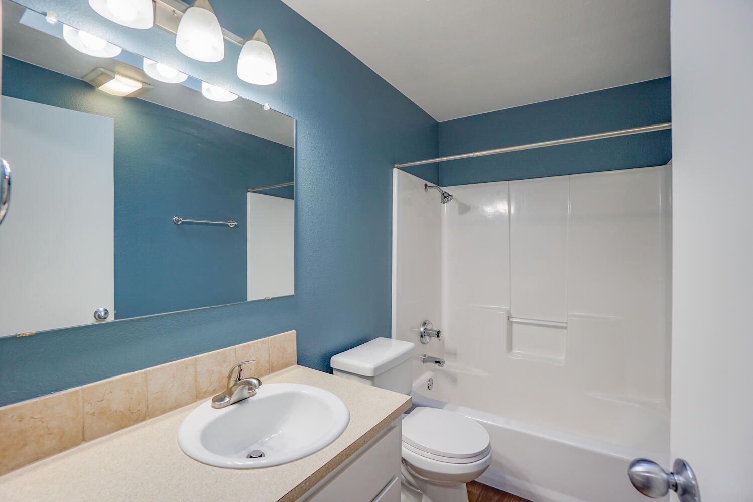 Bathroom with blue walls, white fixtures, and a tan countertop.