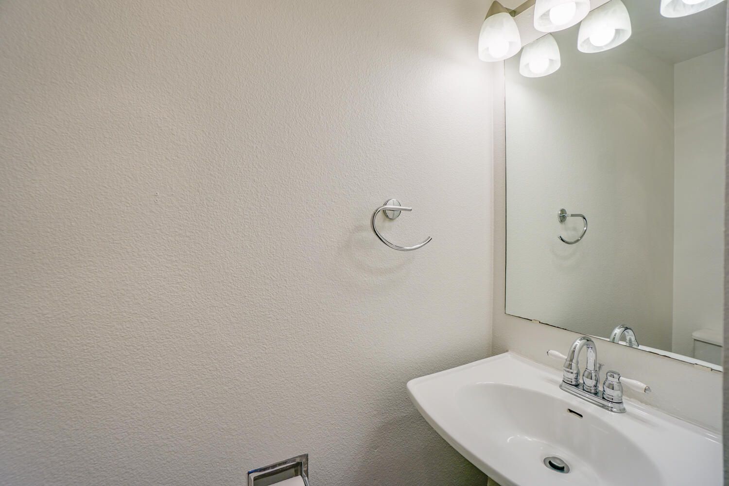 Small white bathroom with a sink, mirror, towel rack, and light fixture.