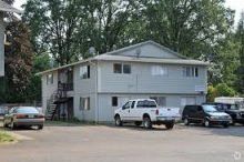 A white truck is parked in front of a white apartment building.