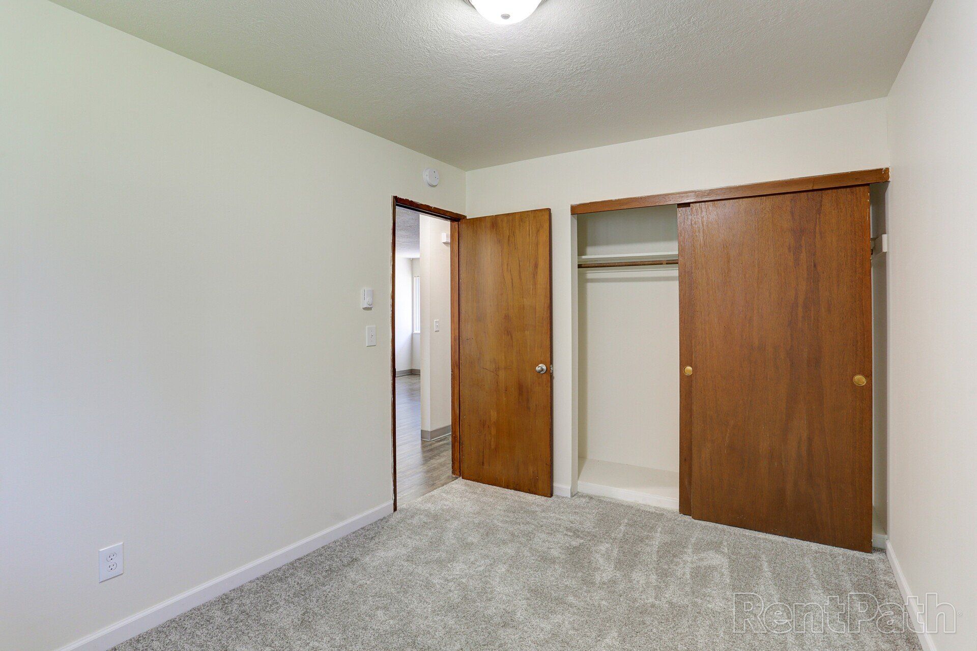 An empty bedroom with two closets and a carpeted floor.