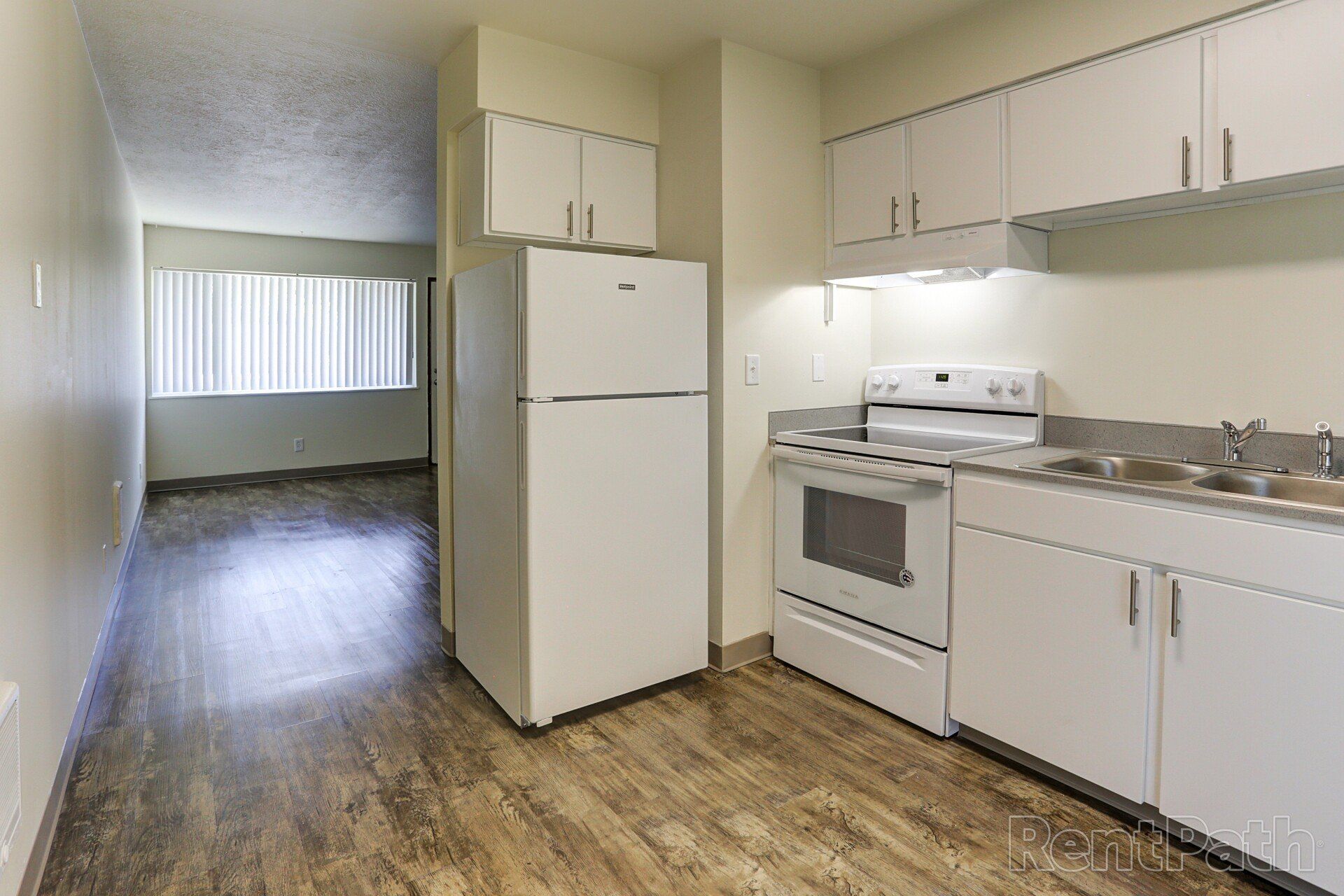 A kitchen with a refrigerator , stove , sink and cabinets.