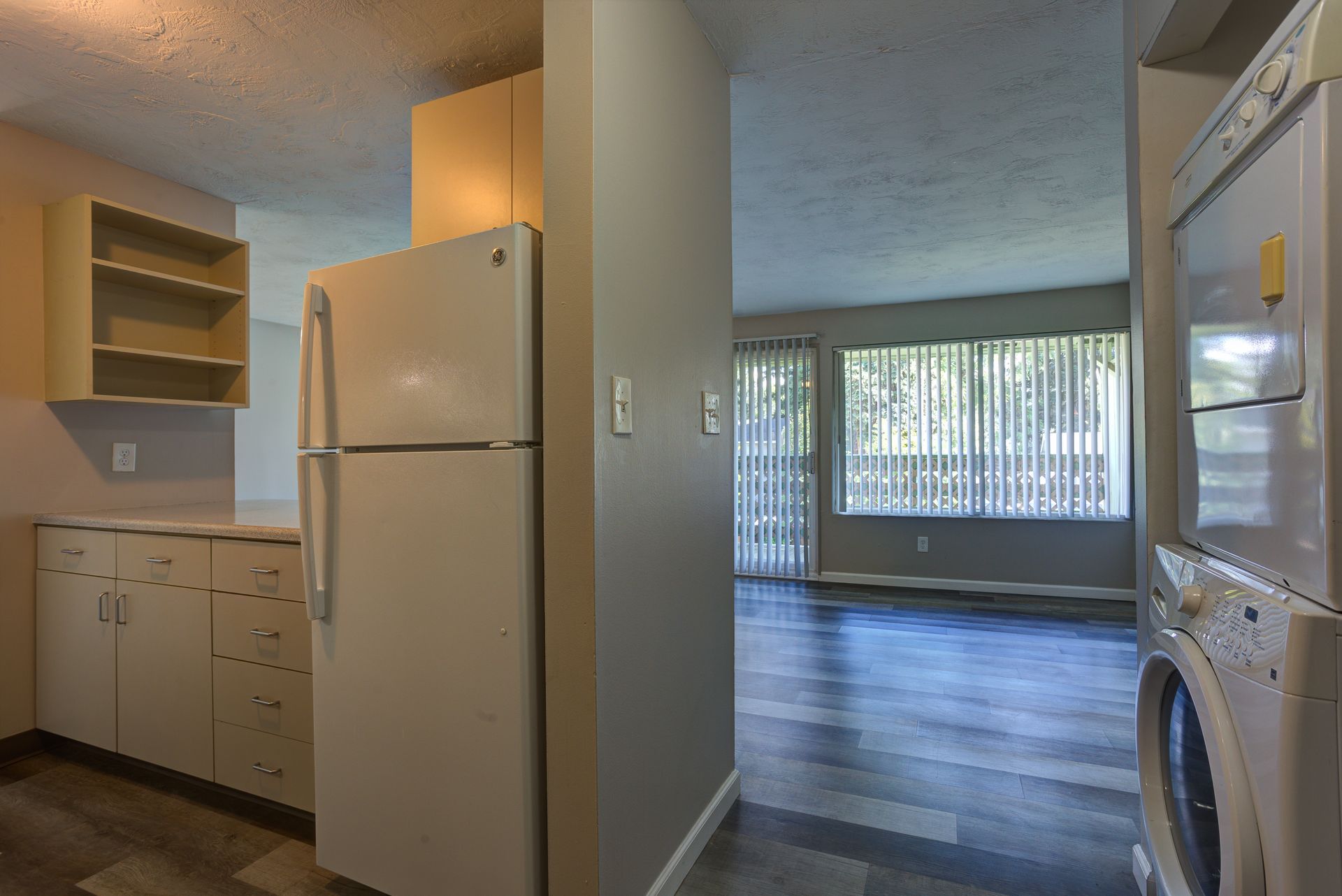 A kitchen with a refrigerator , washer and dryer stacked on top of each other.