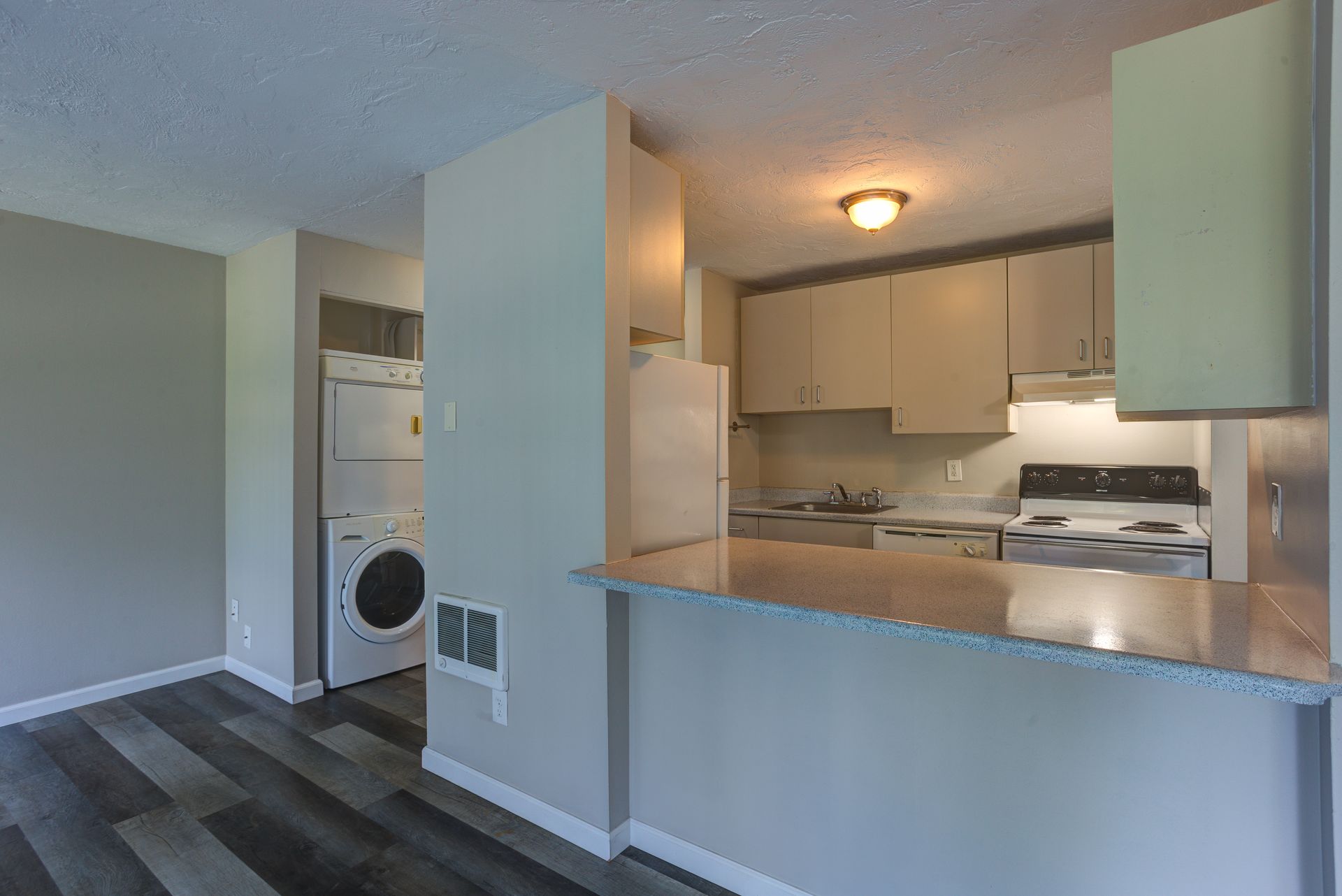A kitchen with a refrigerator , stove , sink , and washer and dryer.