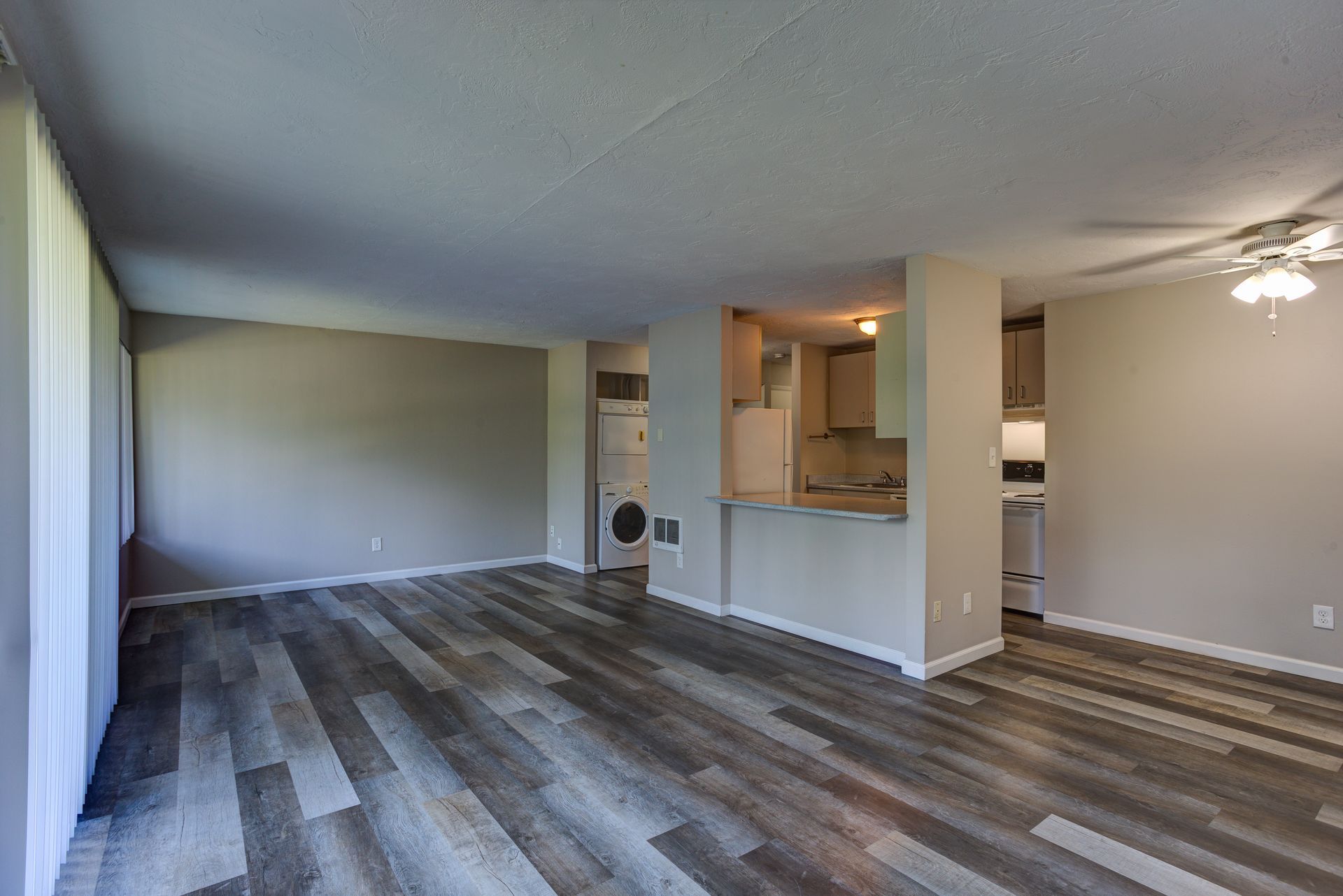 An empty living room with hardwood floors and a ceiling fan.