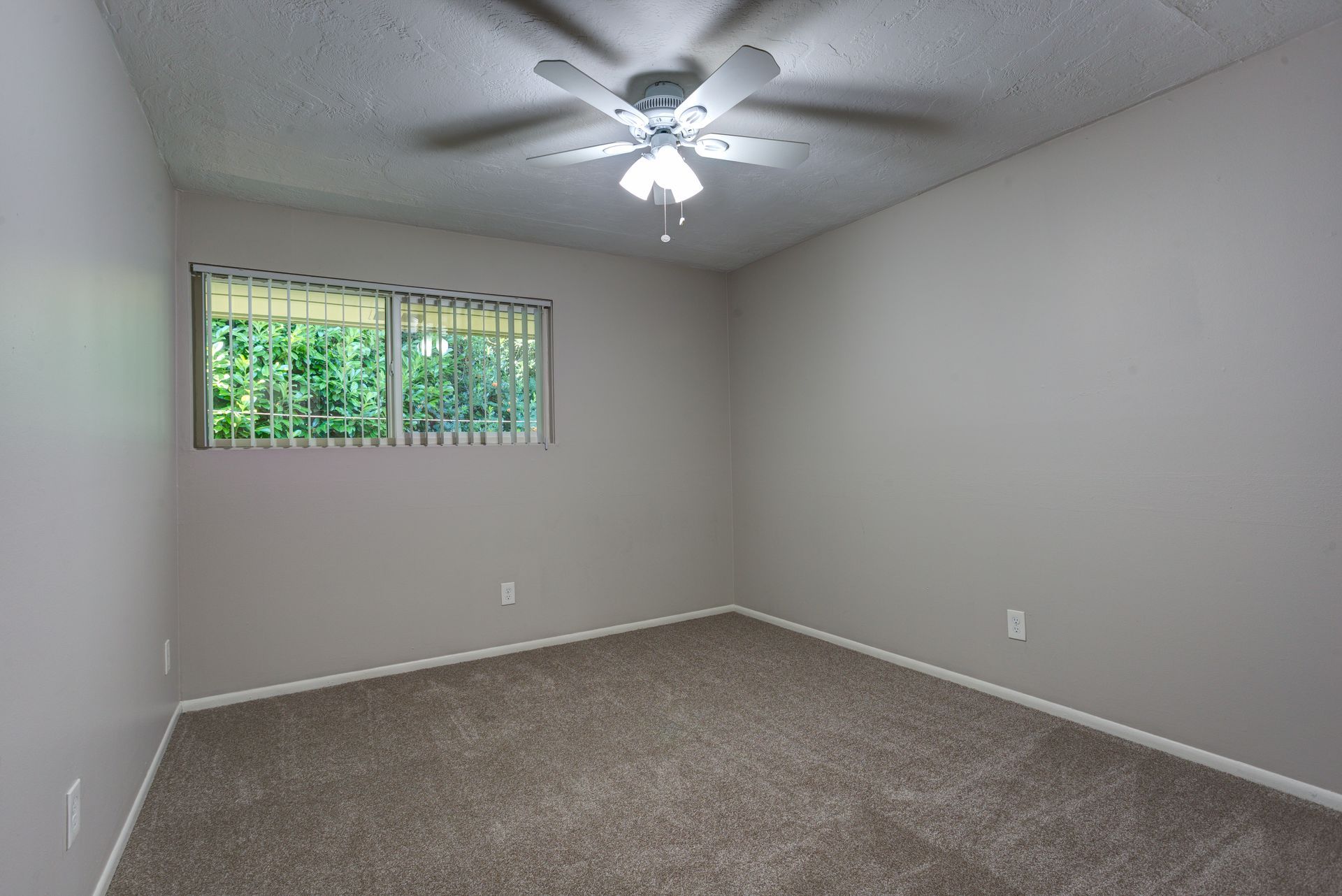 An empty bedroom with a ceiling fan and a window